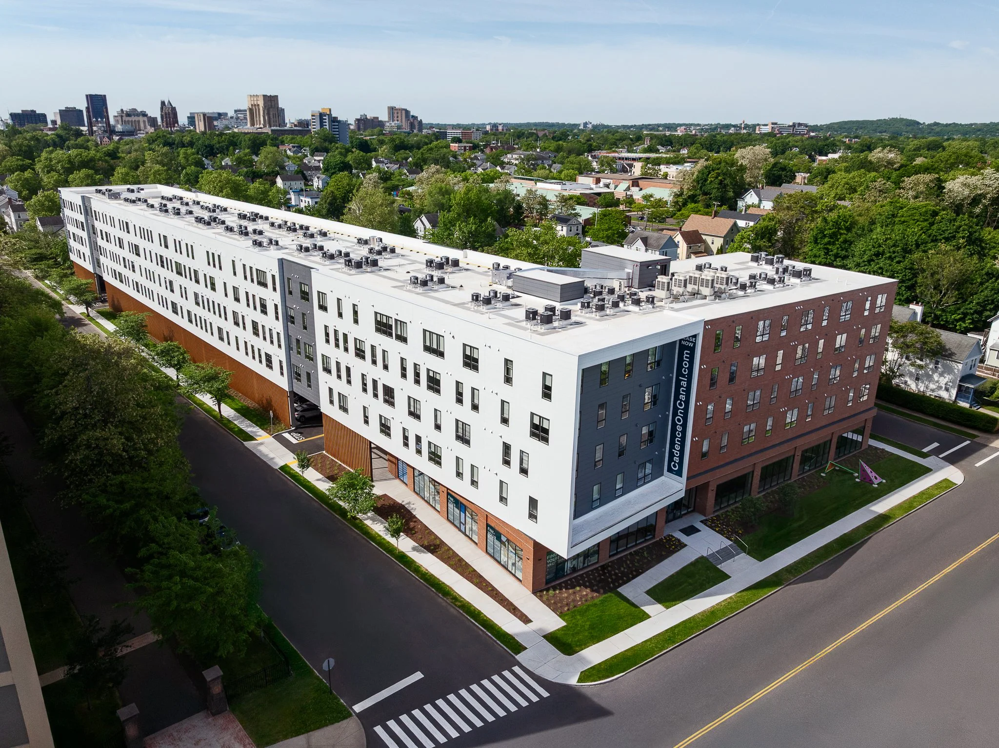 Aerial drone view of the sunlit corner entrance and brick wing.