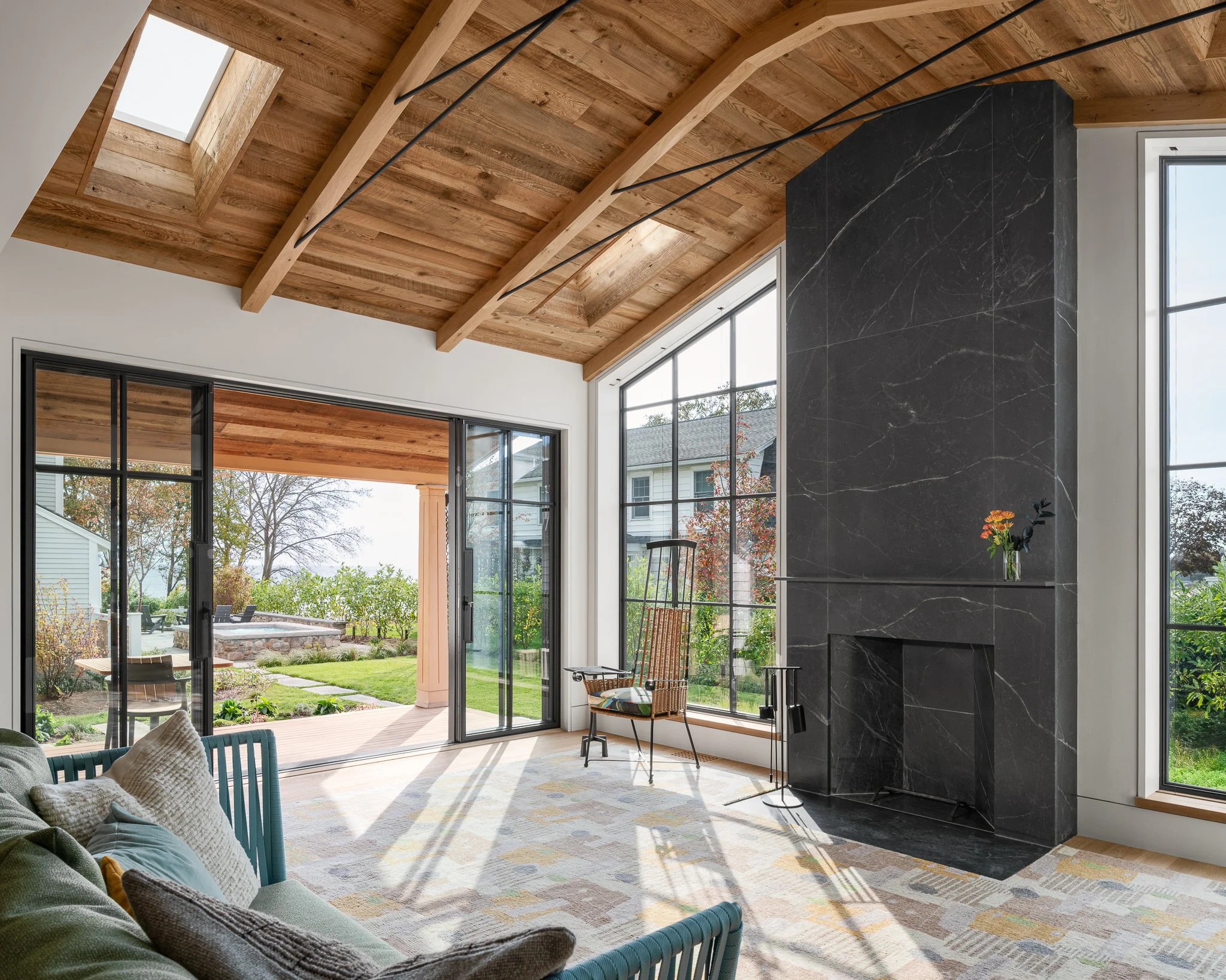 Sunlit great room with skylights, a stone fireplace and sliding doors opening onto the lawn.
