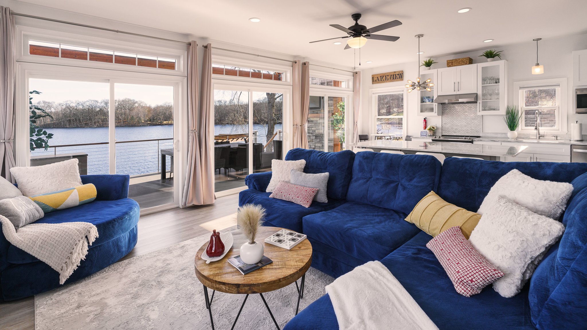 Living room with a blue sectional sofa and wide windows overlooking the lake.