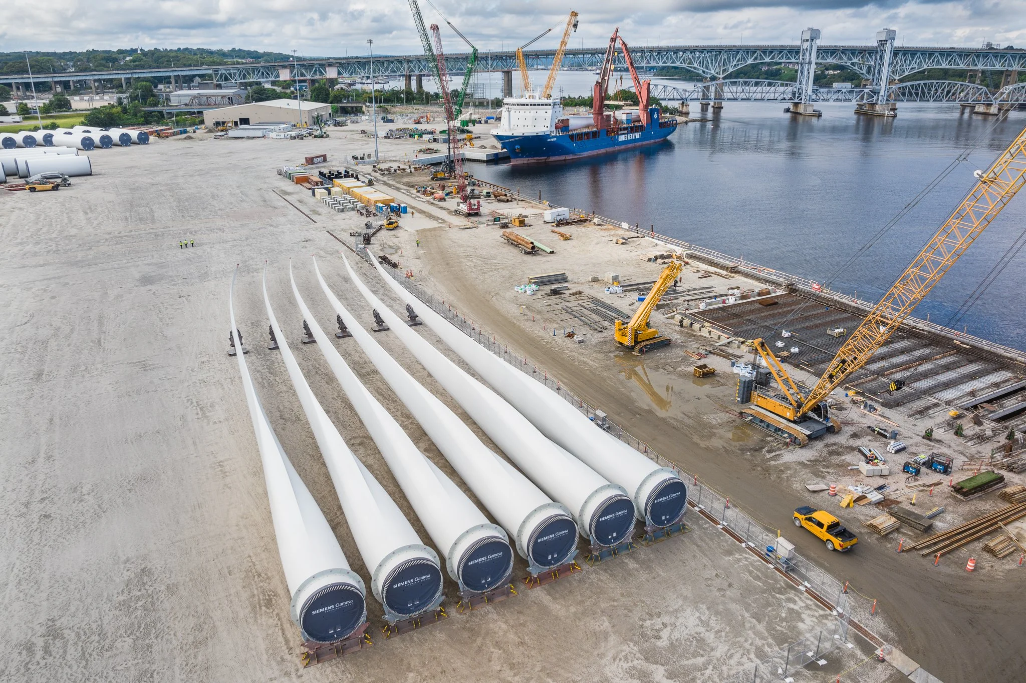 Aerial drone view of wind turbine blades, a cargo ship and the Gold Star Bridge.
