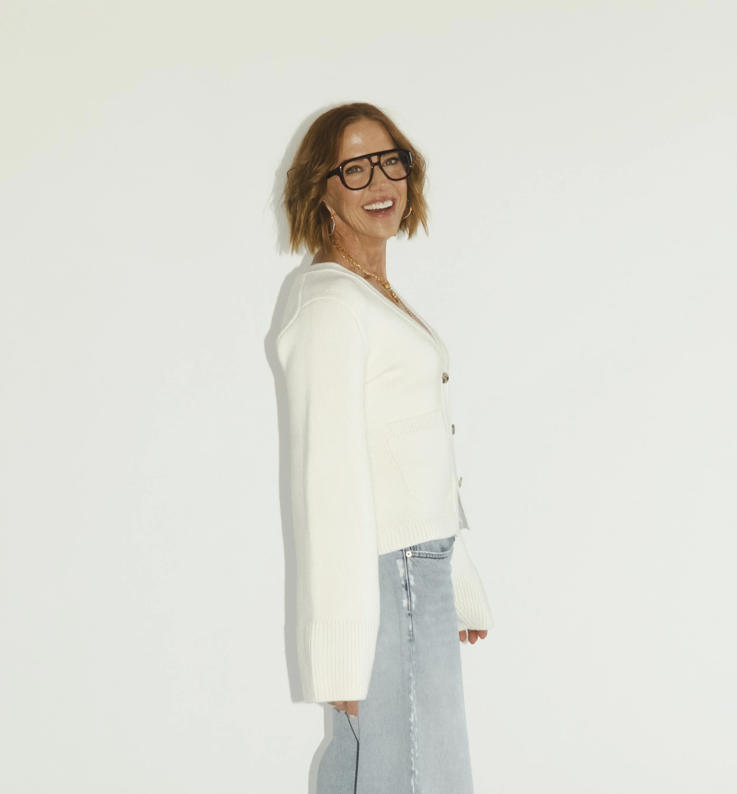 Sarah Schmidt wearing glasses and a white sweater, smiling while looking directly at the camera.