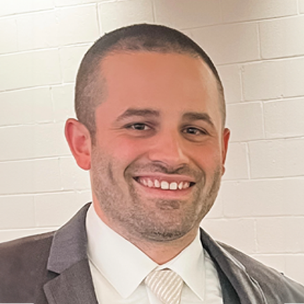 Mr. Greggory Eichler smiling in front of white wall
