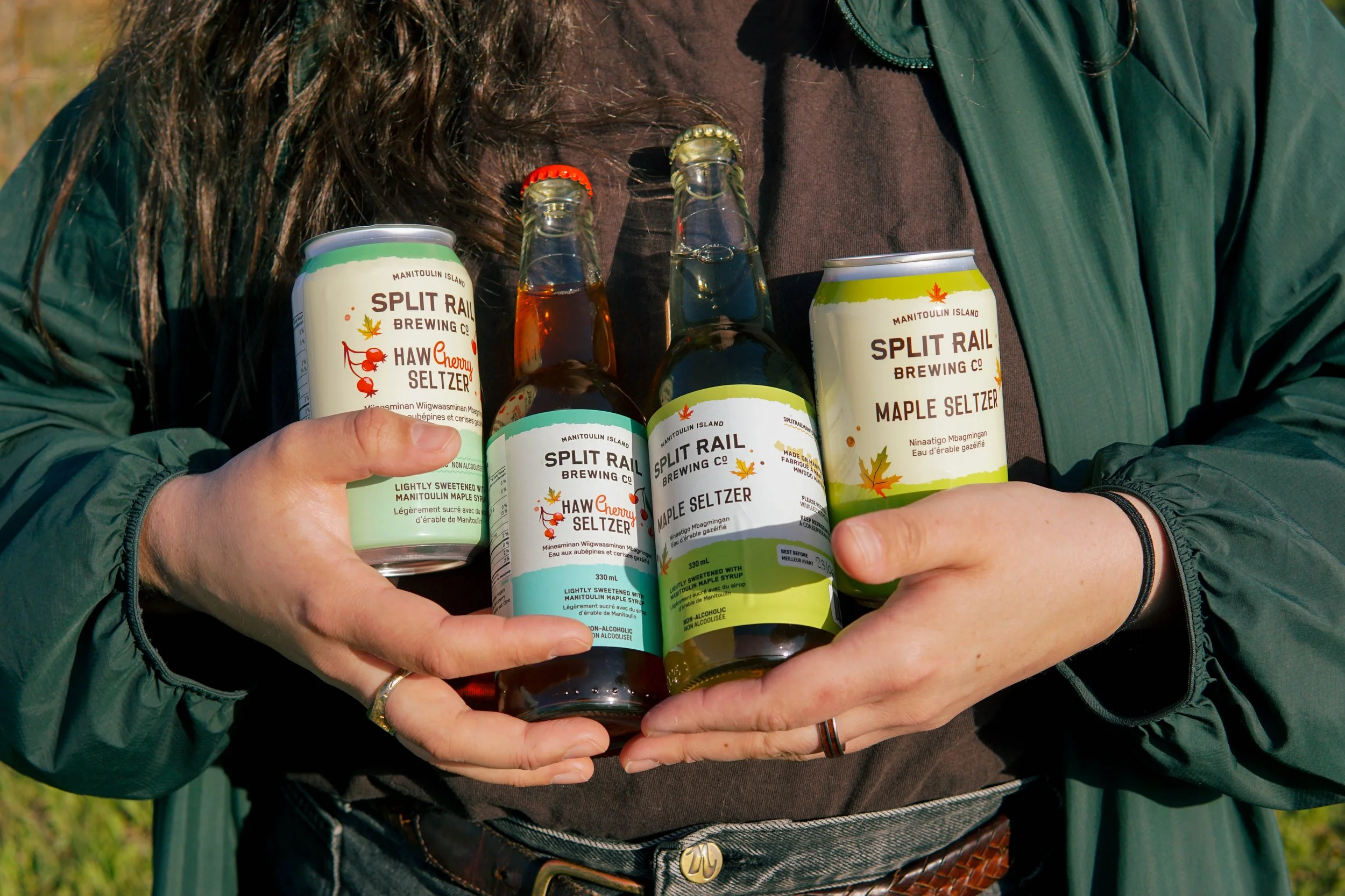 Katelyn holding the glass bottles and aluminum cans in the sun.