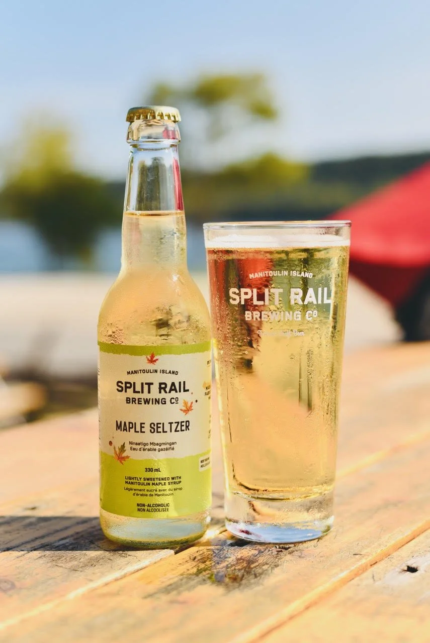 Maple Water Seltzer bottle in the sun, in front of Gore Bay
