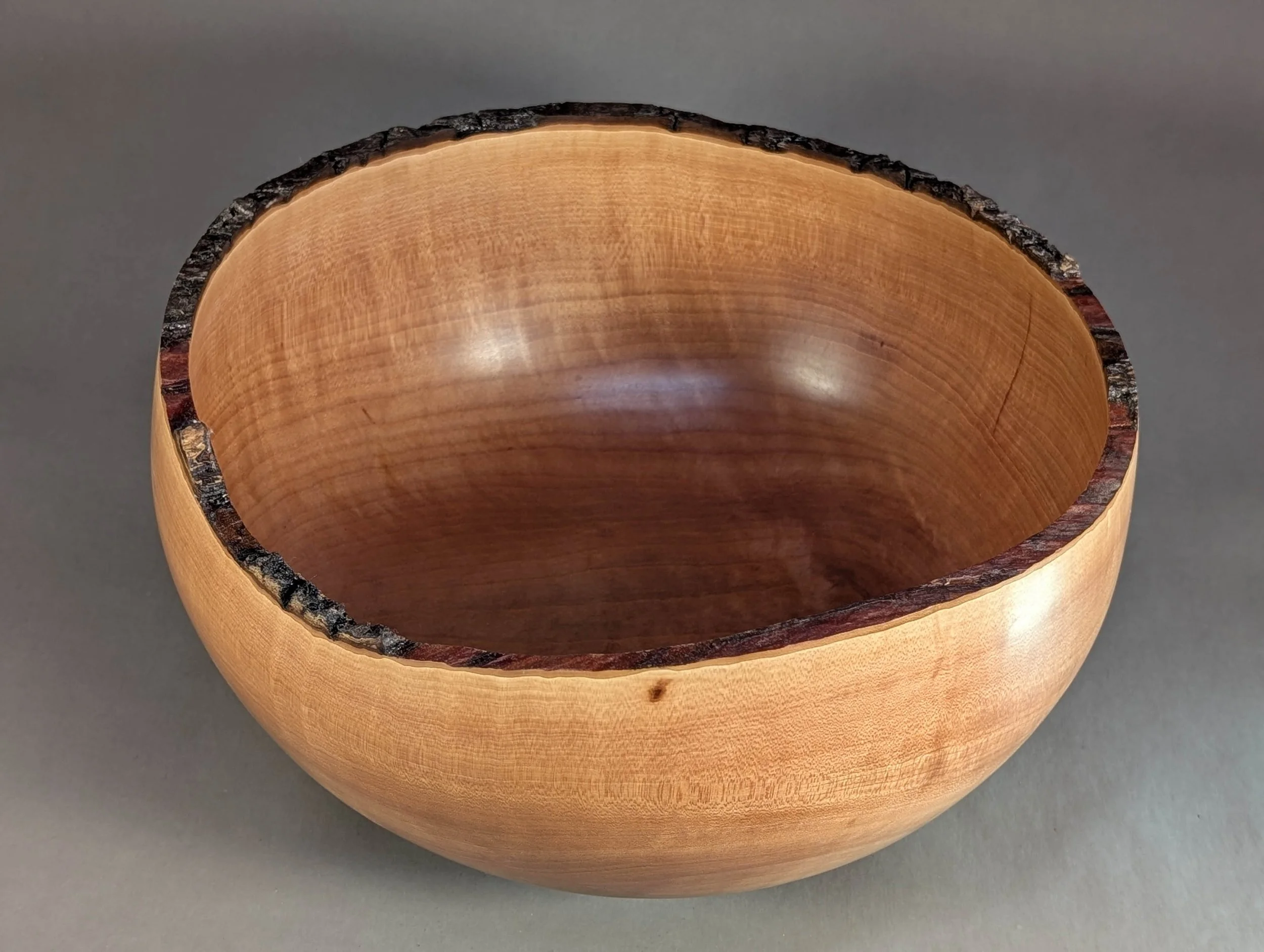  This large, thin-walled decorative bowl is turned from seasoned Madrone wood highlighting the wood's subtle grain and warm, natural hues.