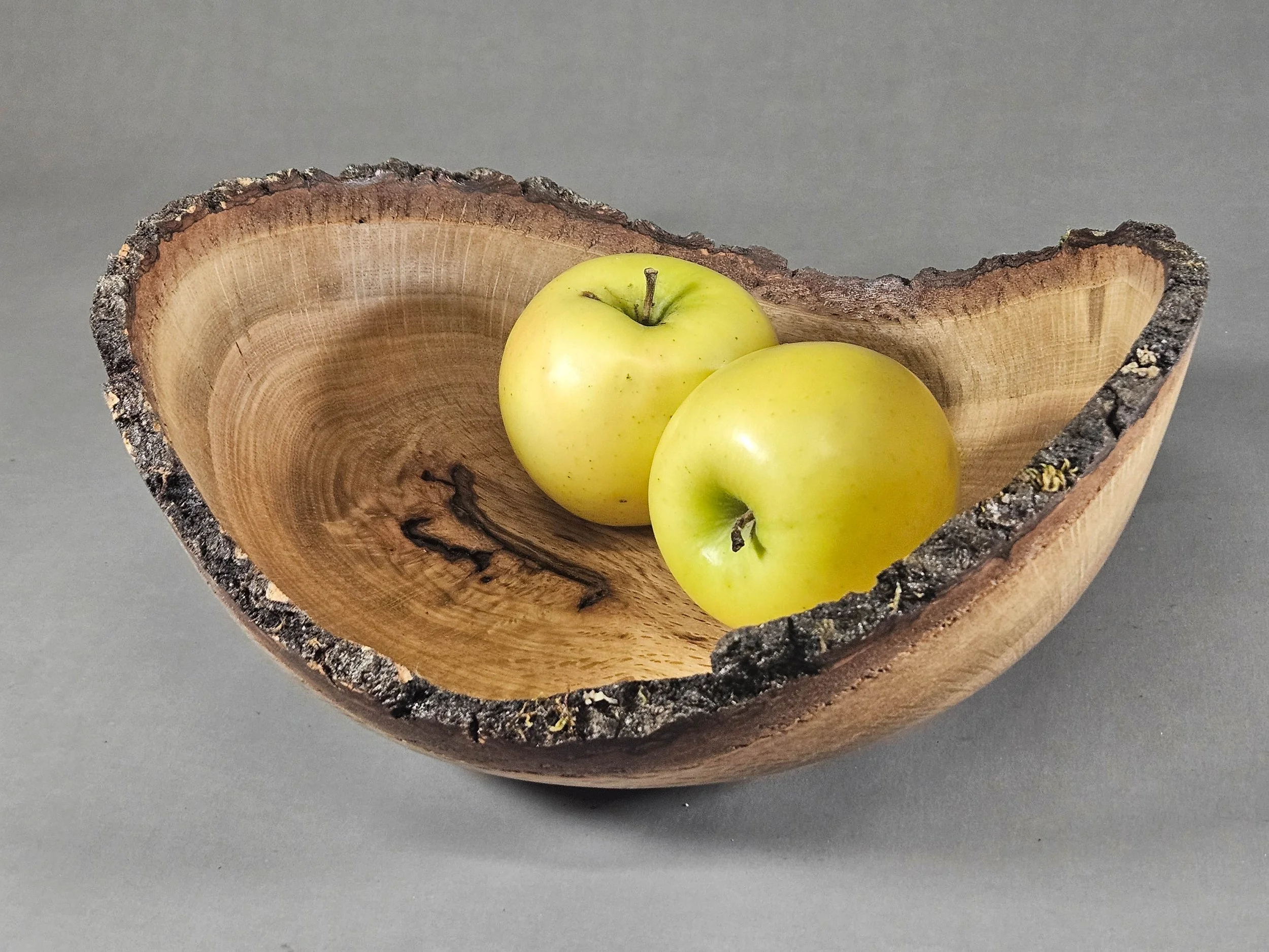 Hand-turned from the wood of a 250-year-old oak tree, this bowl features a delicate, thin-walled construction and a preserved natural edge. The tree's slow growth has resulted in an unusually dense and complex grain, creating a beautiful decorative p