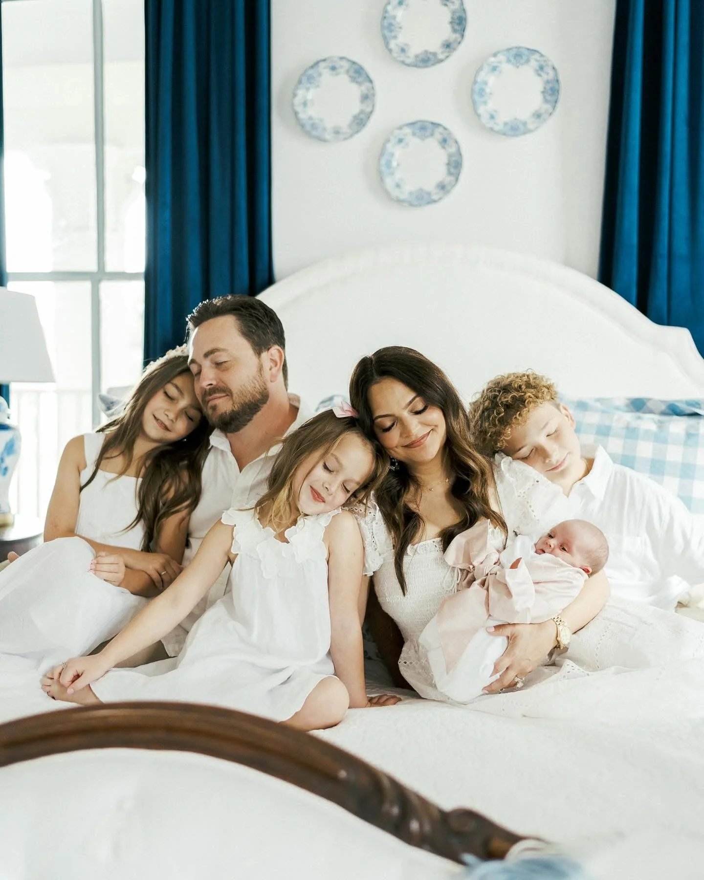 A large family of six, including two adults and four children, sits on a bed in a bedroom at The Bingham Estate. Perfect place for family photoshoot in North Dallas. McKinney photographers have photoshoots at the unique hotel property.