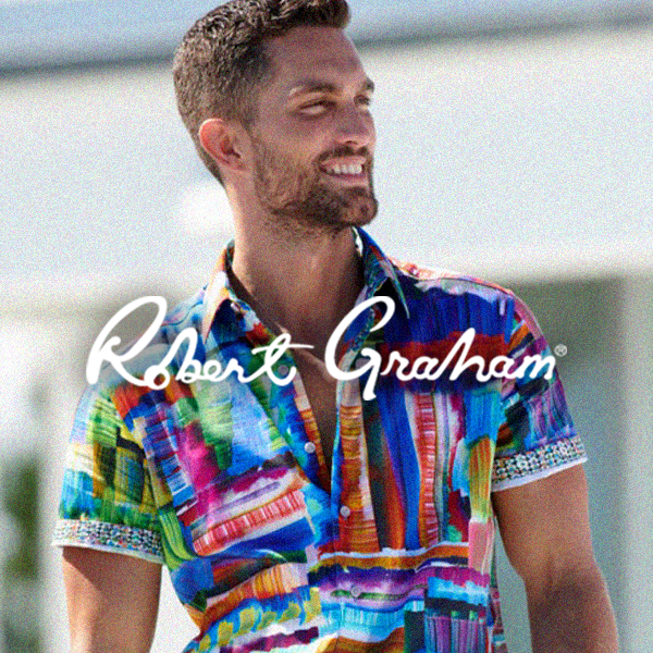 Man with short hair and beard smiling outdoors, wearing a colorful, patterned button-up shirt.