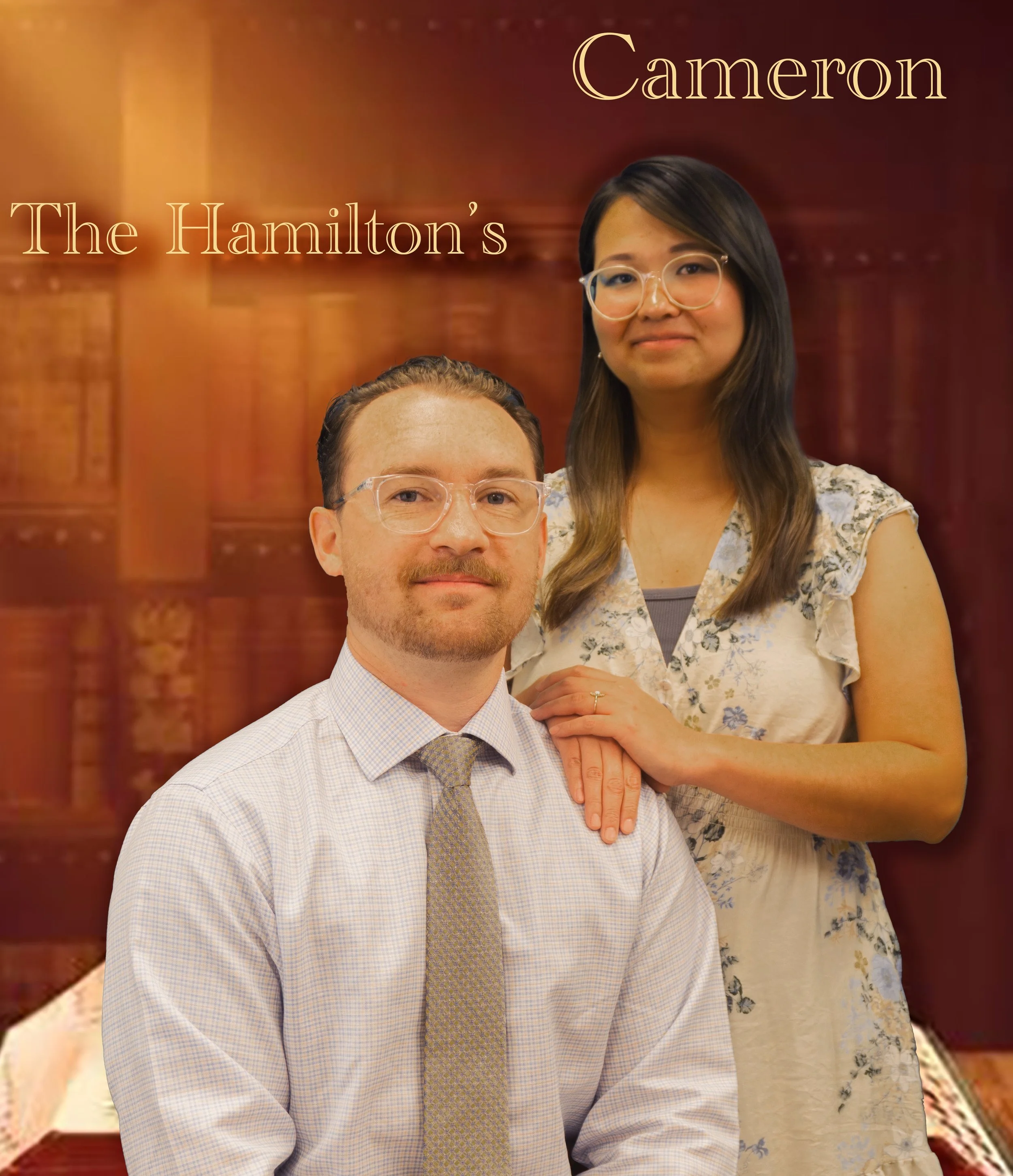 Two people pose together in front of a wooden background. The man in the foreground is wearing glasses, a light-colored checkered shirt, and a patterned tie. The woman behind him has long dark hair, glasses, and is wearing a floral dress.
