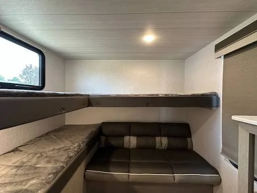 Salem 273QBXL bunk room with upper bunks along two walls, a lower bunk, and a jiffy sofa, lit by a ceiling light and side window.