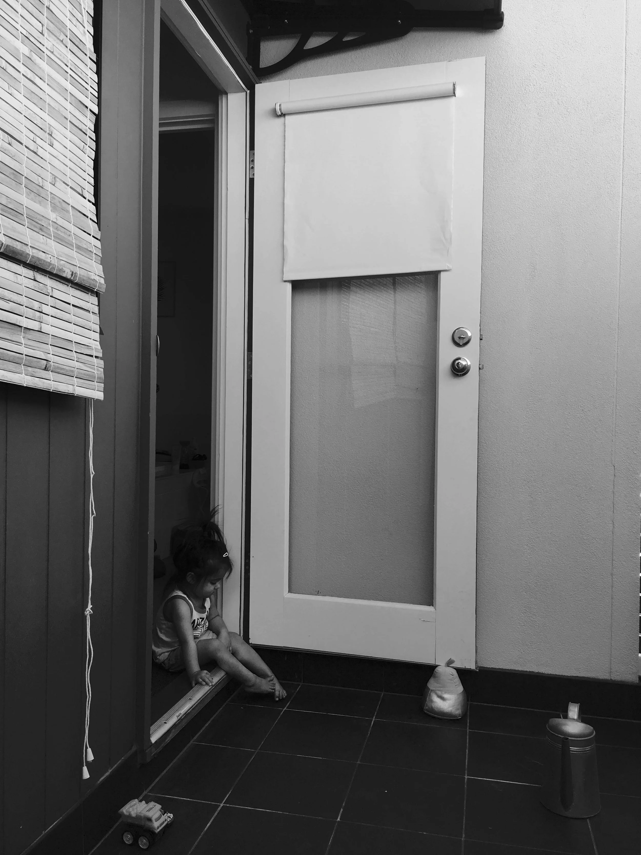 Toddler sits quietly in a doorway during an at-home family photography session.