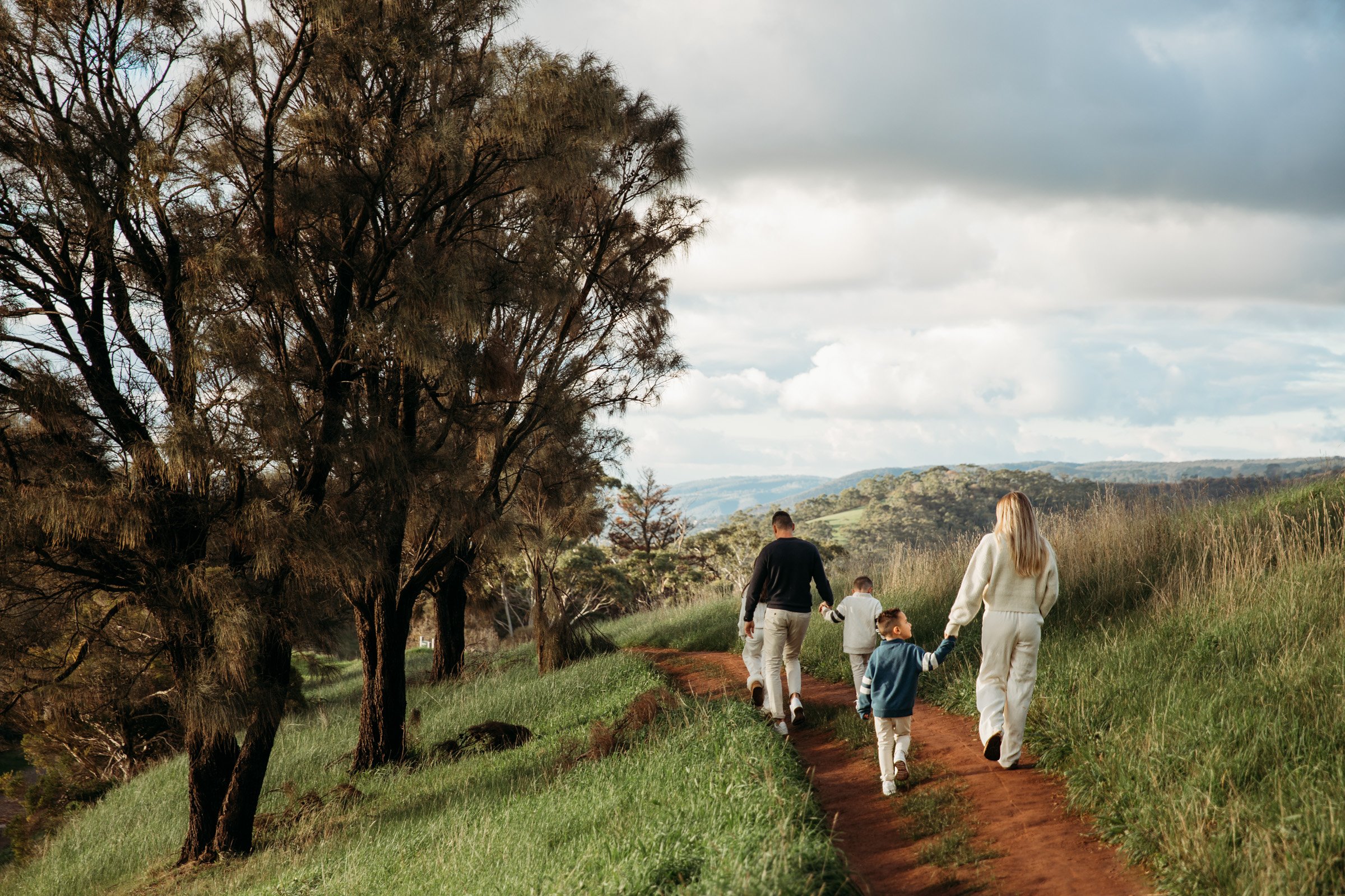 Family of four walking along a grassy trail through the Adelaide Hills.