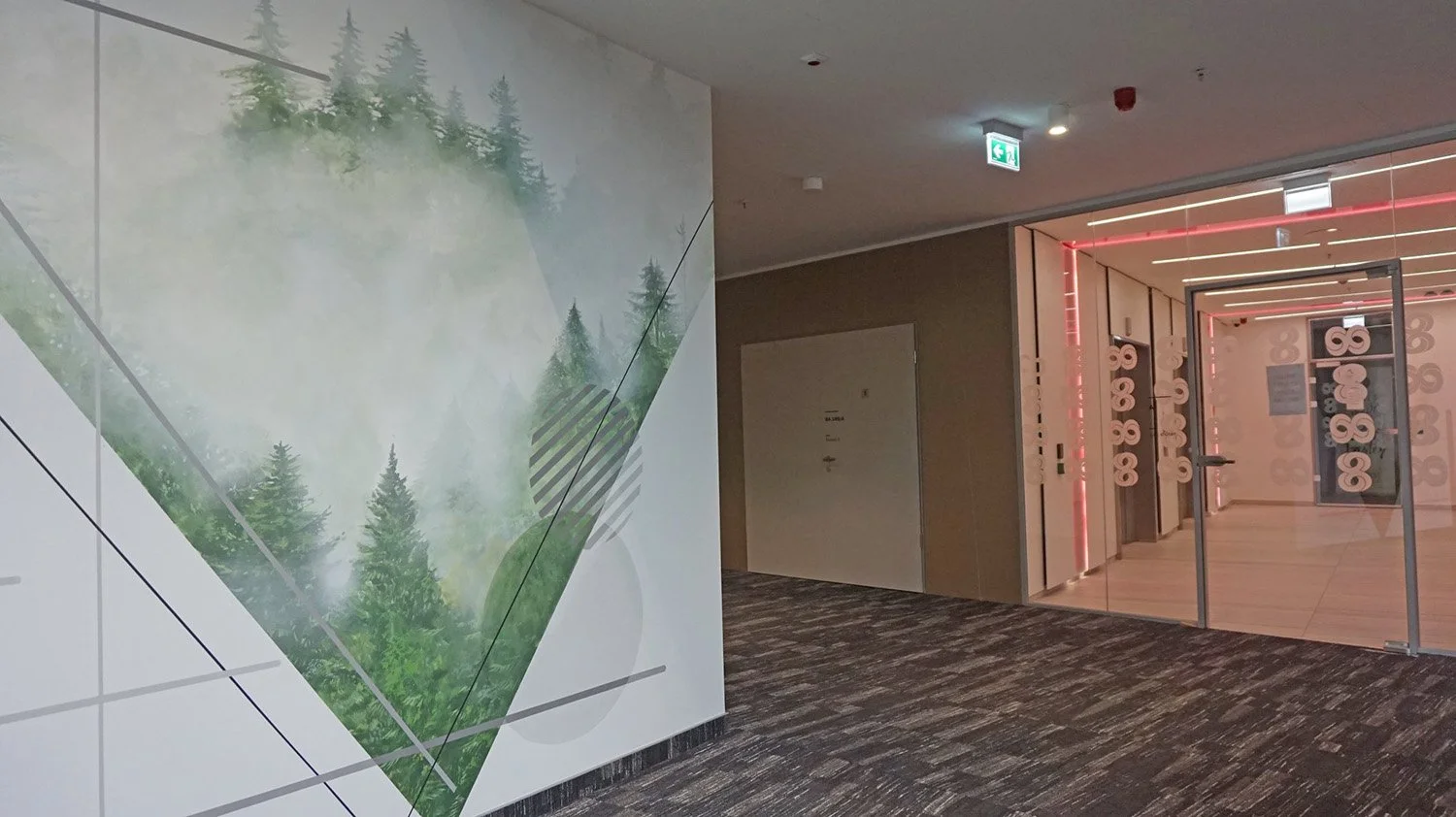 An indoor space with a wall mural of a foggy forest scene on the left, and a glass door with the number 8 enclosed by circular patterns on the right, leading to another room with red lighting accents.