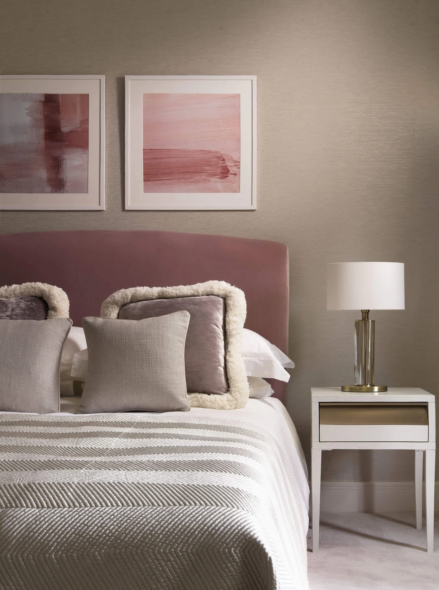 Bed and bedside table with warm tones and pink accents