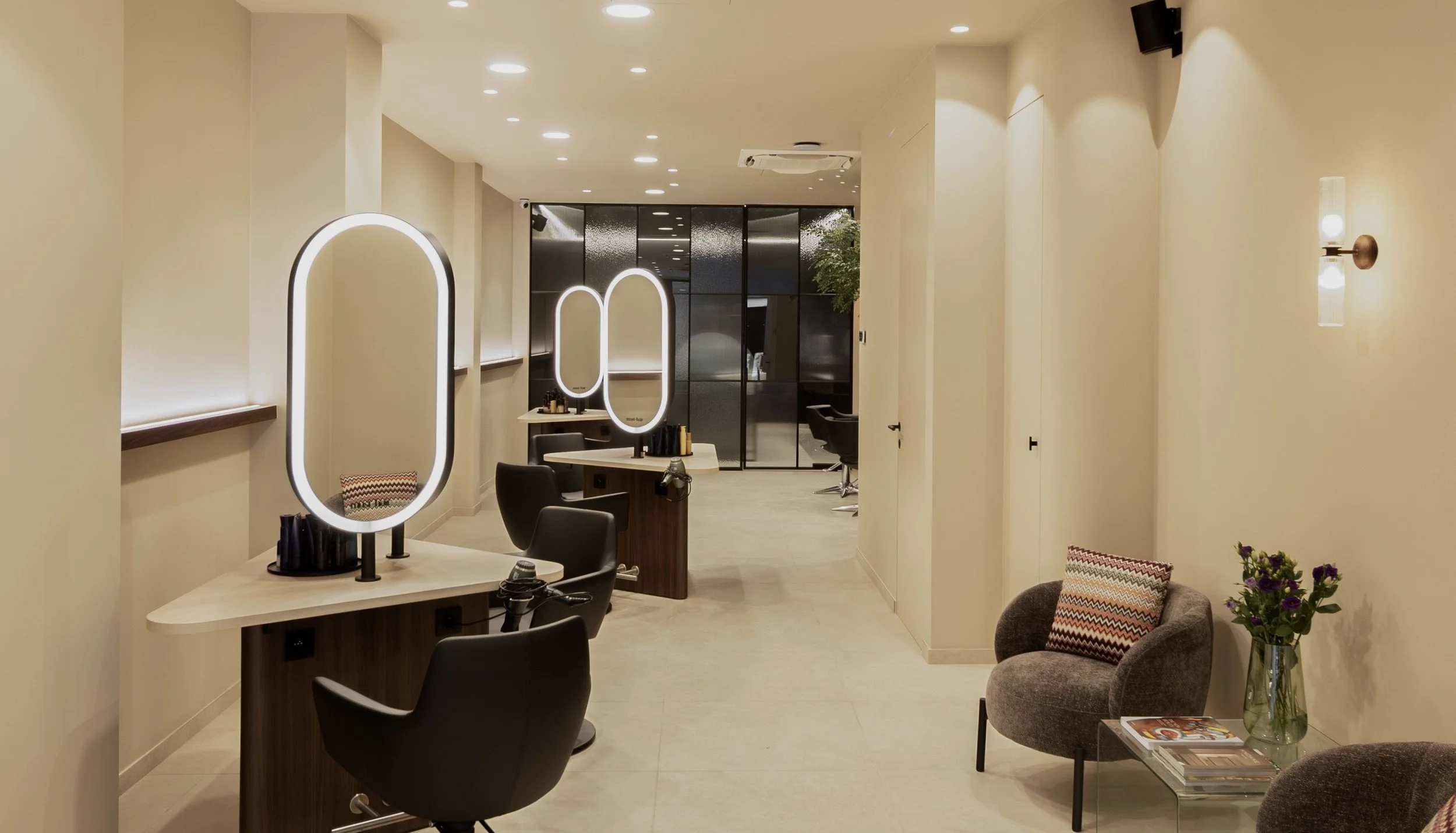 Interieur van een kapsalon met spiegelstations en zitplaatsen.