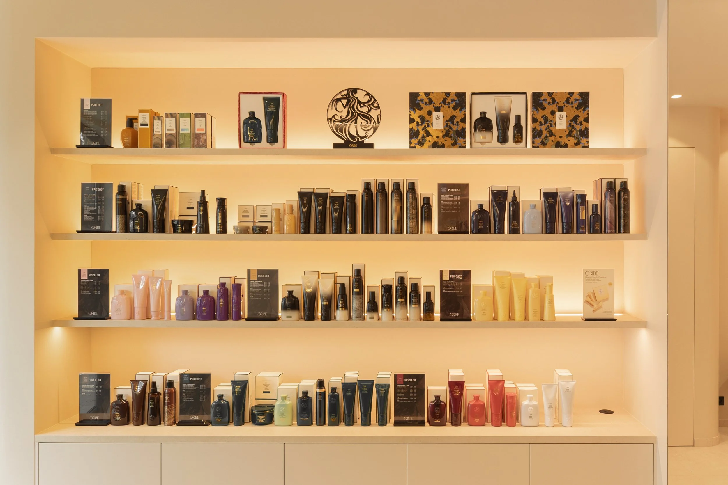 Schapen met verschillende haarproducten en cosmetica in een winkel, verdeeld over vier verlichte planken.