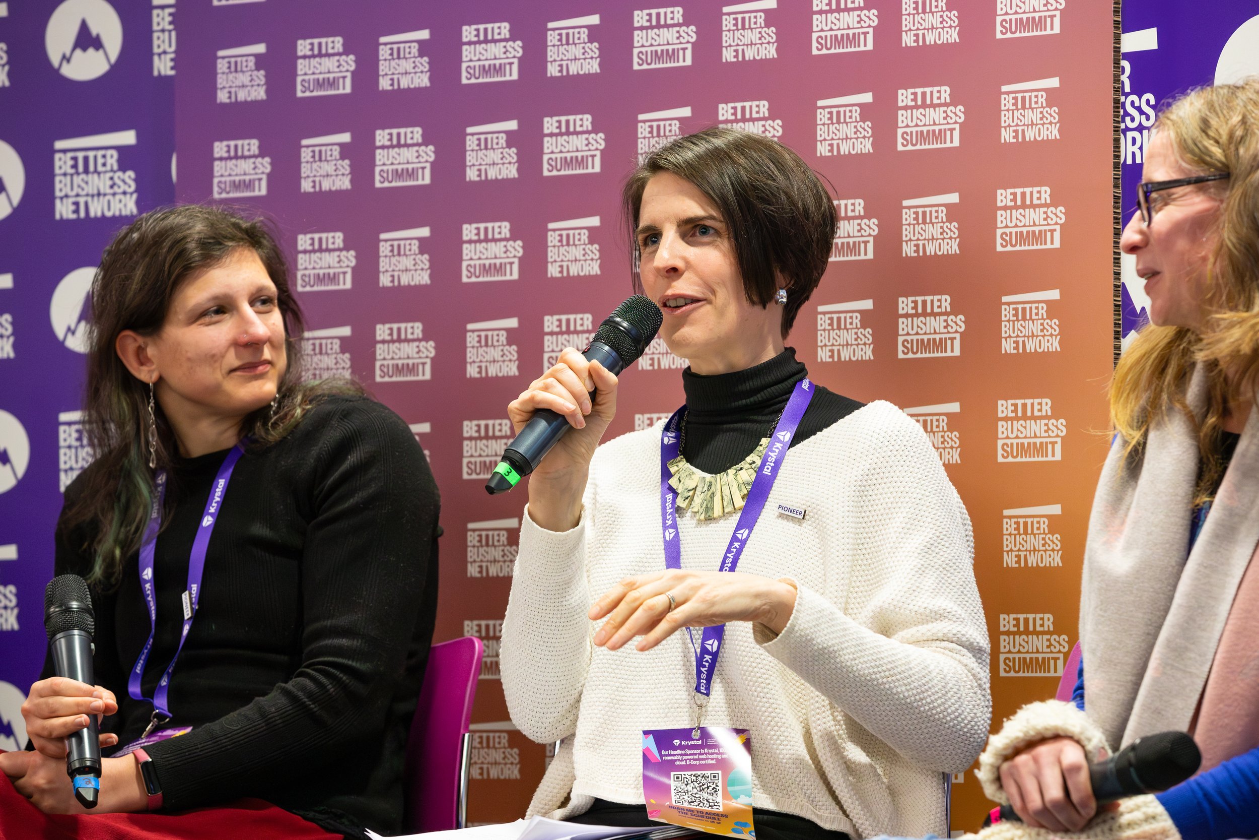 Panel discussion at Better Business Network event with three women holding microphones.