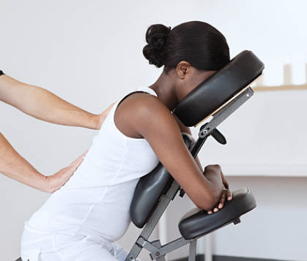 Une femme reçoit un massage du dos sur chaise ergonomique en entreprise