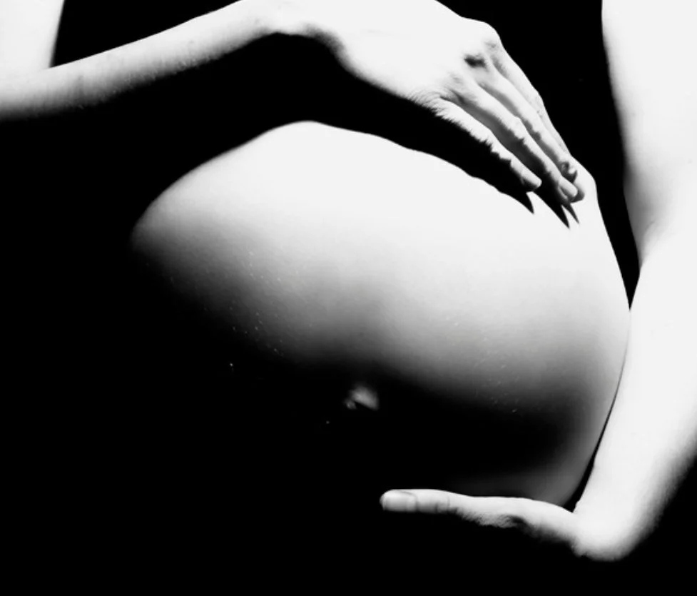 femme enceinte se tenant le ventre sur une photo en noir et blanc