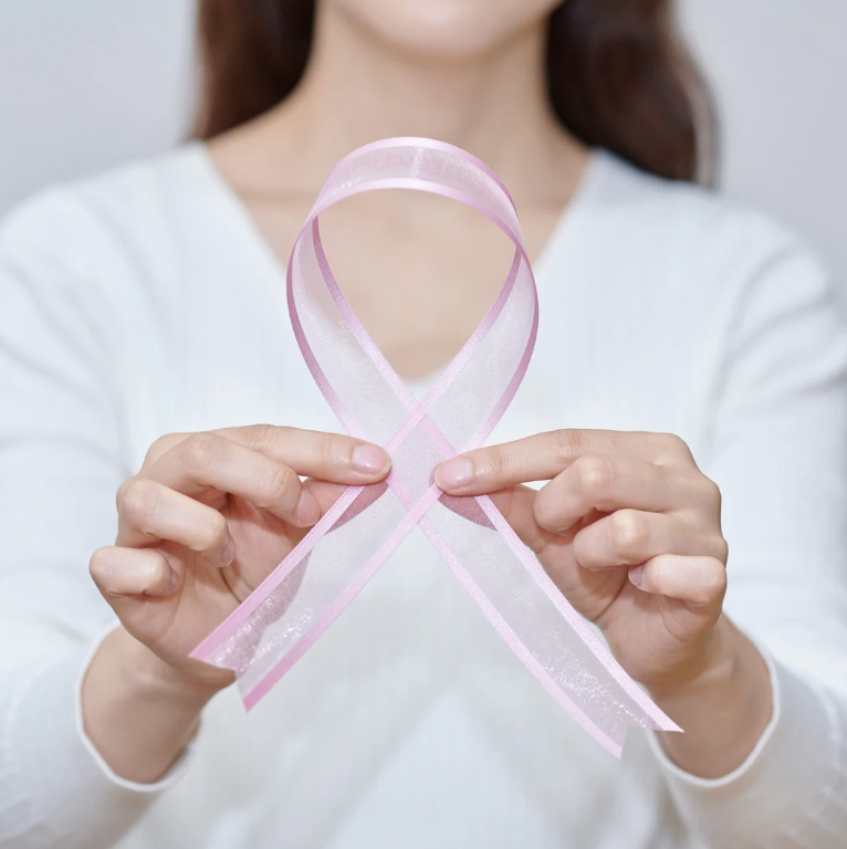 femme tenant un noeud rose représentant la lutte contre le cancer du sein