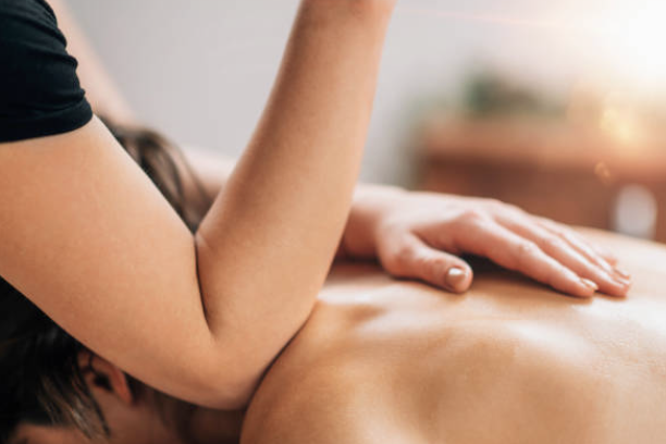 une personne se fait masser le dos par une praticienne qui utilise son coude, dans un cabinet de massage