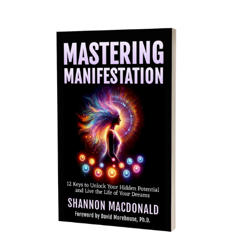 Book cover titled "Mastering Manifestation" by Shannon Macdonald, featuring a colorful, abstract figure with flowing hair and glowing circles, with a subtitle about unlocking potential and living dreams.