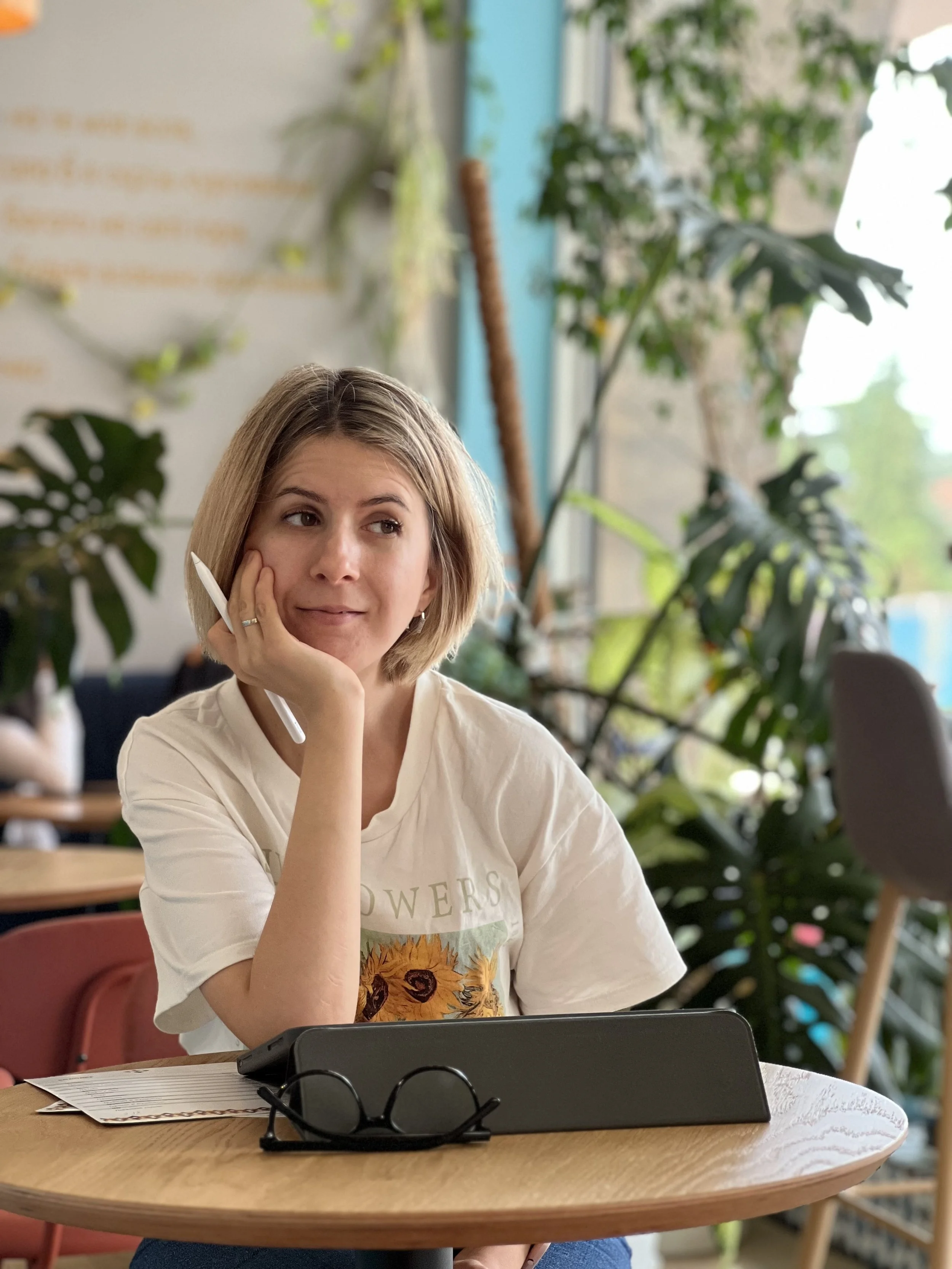 a woman with blonde hair and an ipad and ipad pencil looking off in a coffee studio