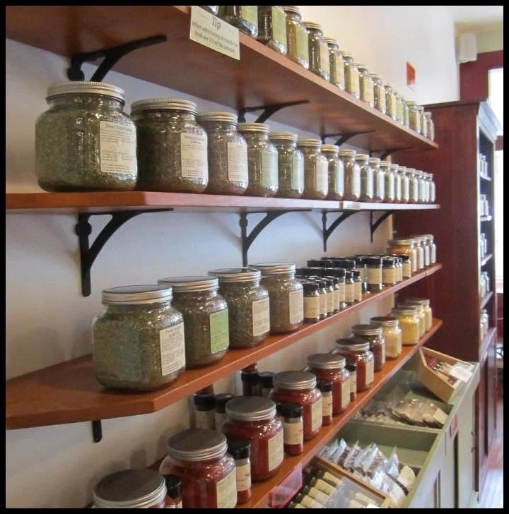 Wall-mounted wood shelves on iron brackets holding spice jars