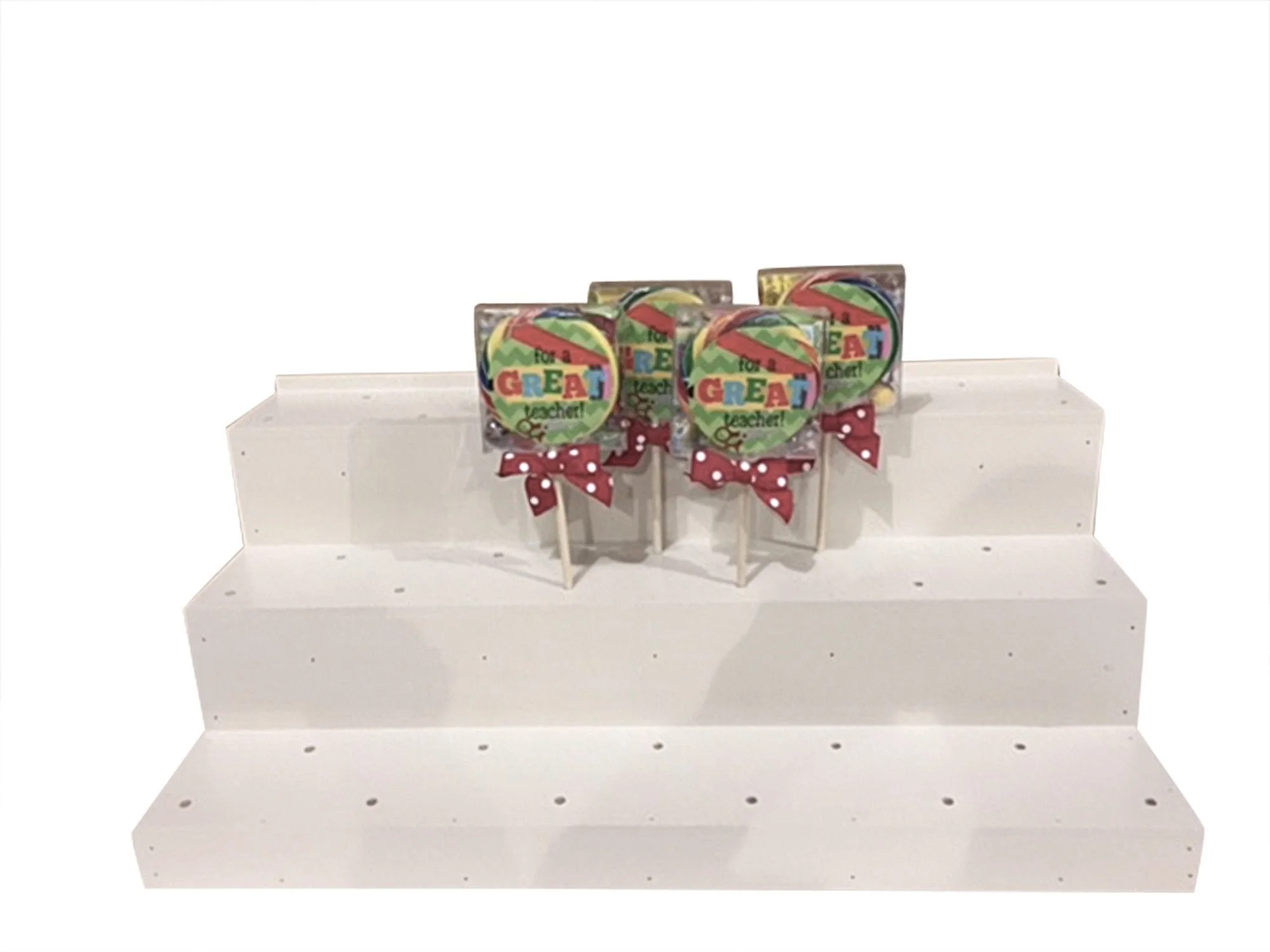 White stepped countertop display with holes for lollipops
