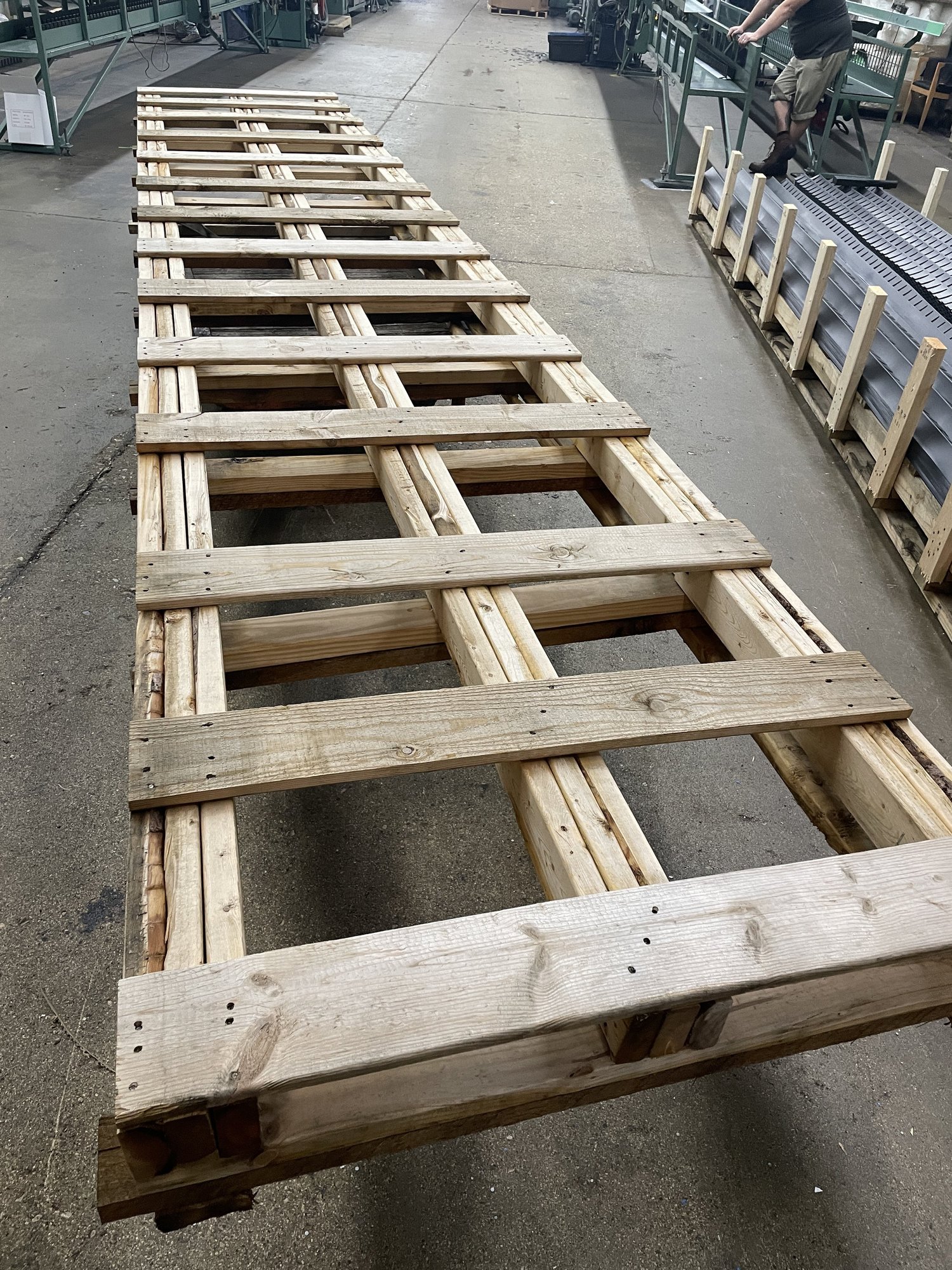 A 226 inch Atlas extra-long pallet on its fifth re-use cycle, weathered but structurally sound, in a manufacturing facility