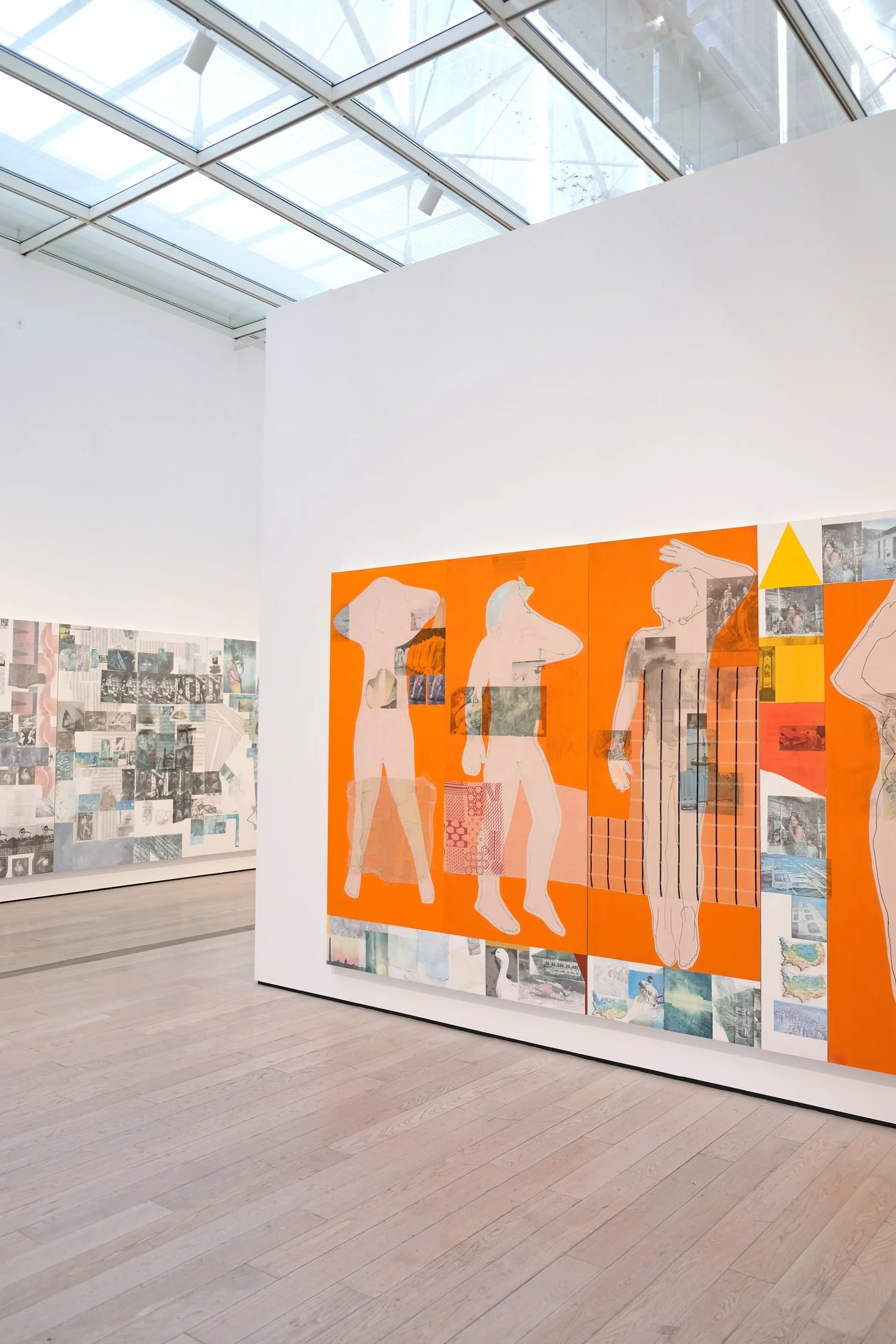Gallery interior with large artwork on white wall featuring abstract, outlined human figures on an orange background and other collage-style art pieces.