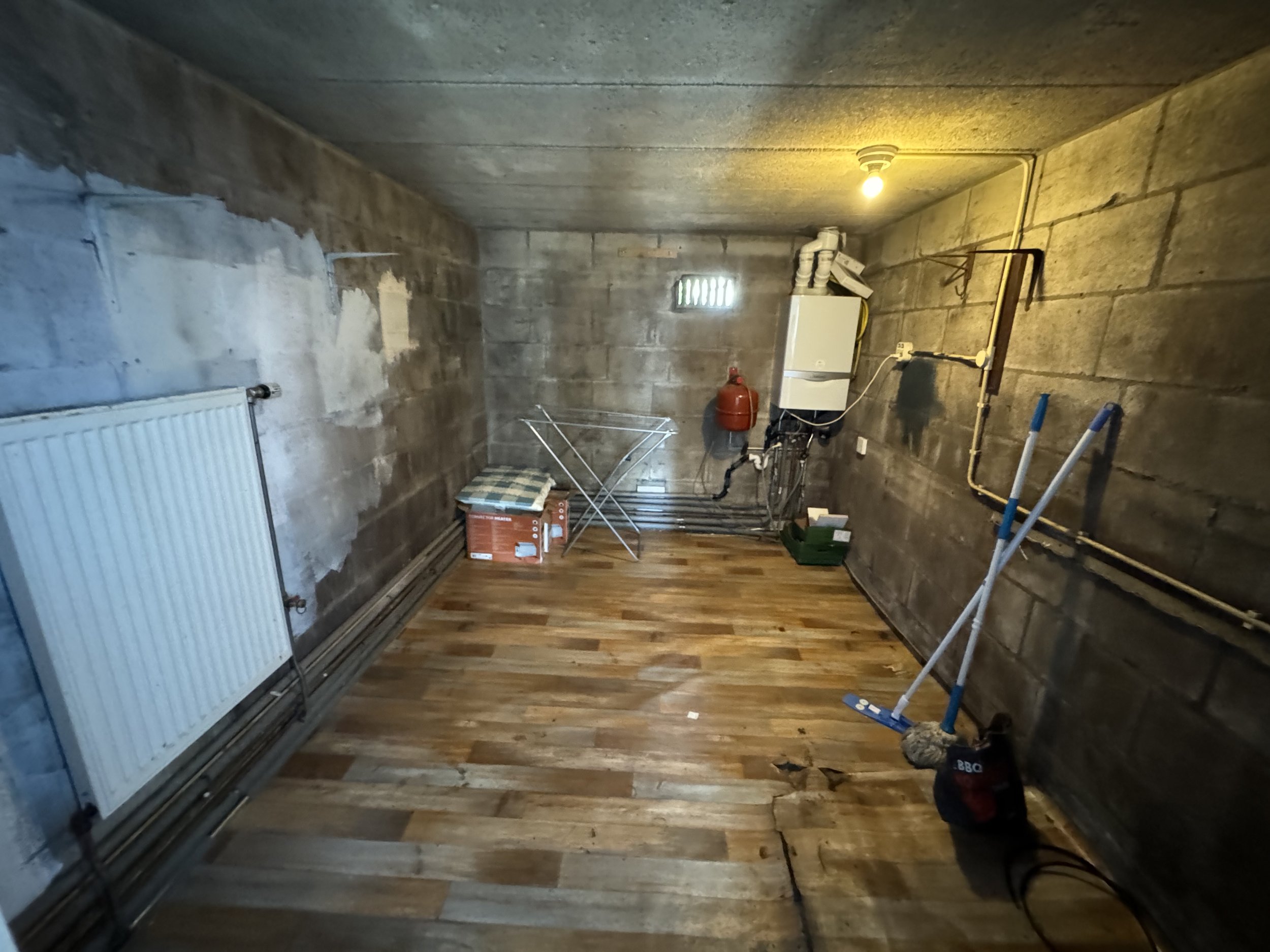 Concrete basement room with storage, heater, and cleaning supplies
