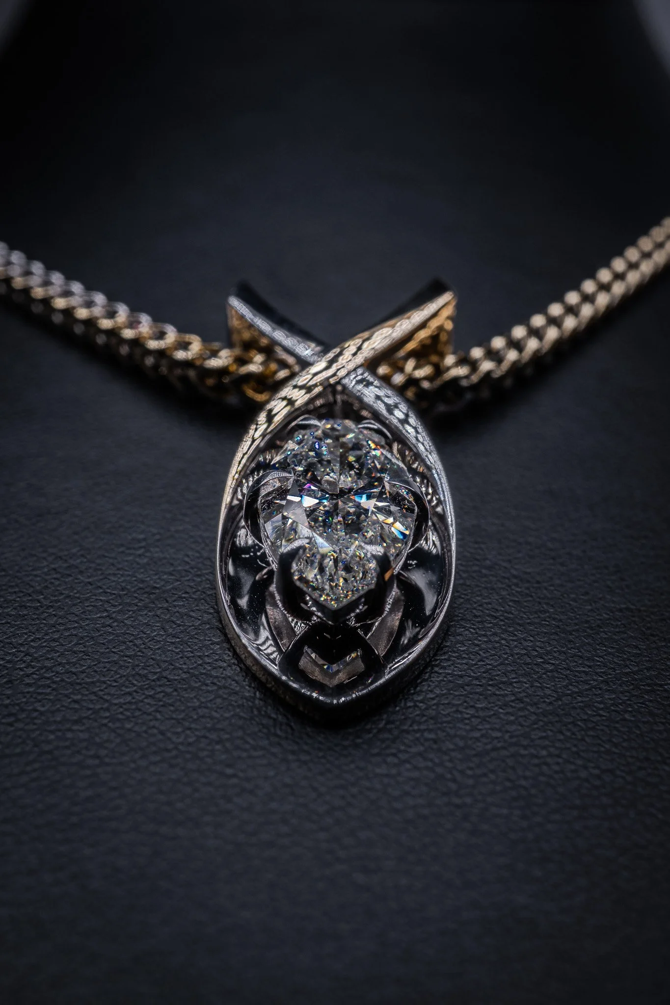 A silver necklace with a heart-shaped diamond pendant on a black textured background.