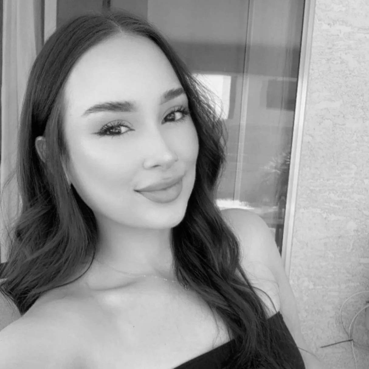 a woman is smiling at the camera slightly over her shoulder