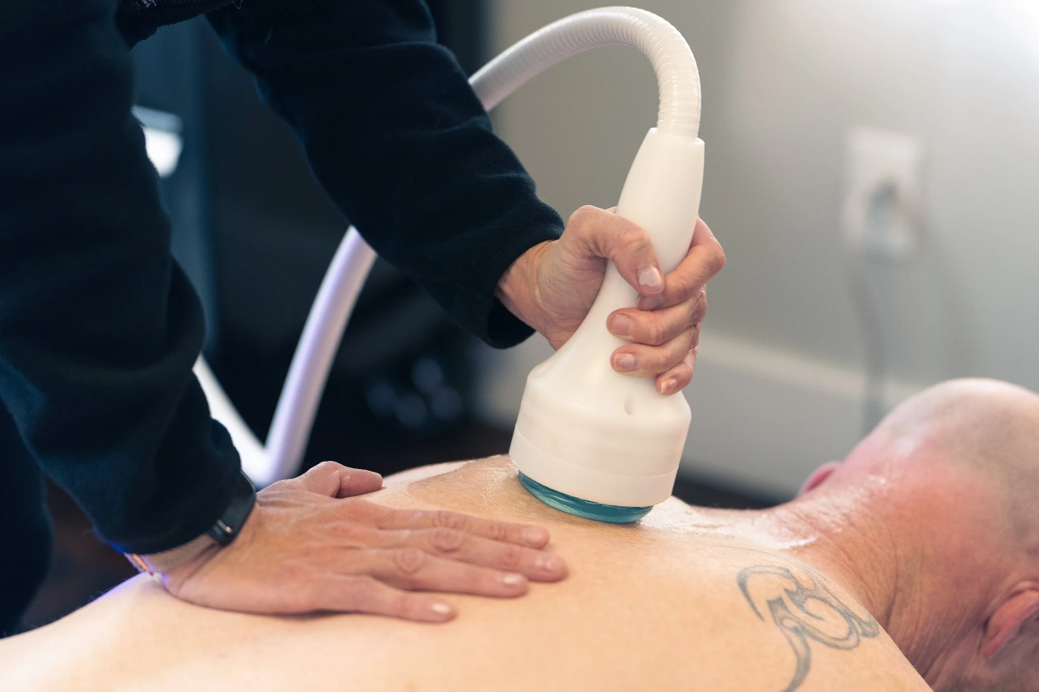 a practitioner uses the pulsewave. it is placed on a bare back