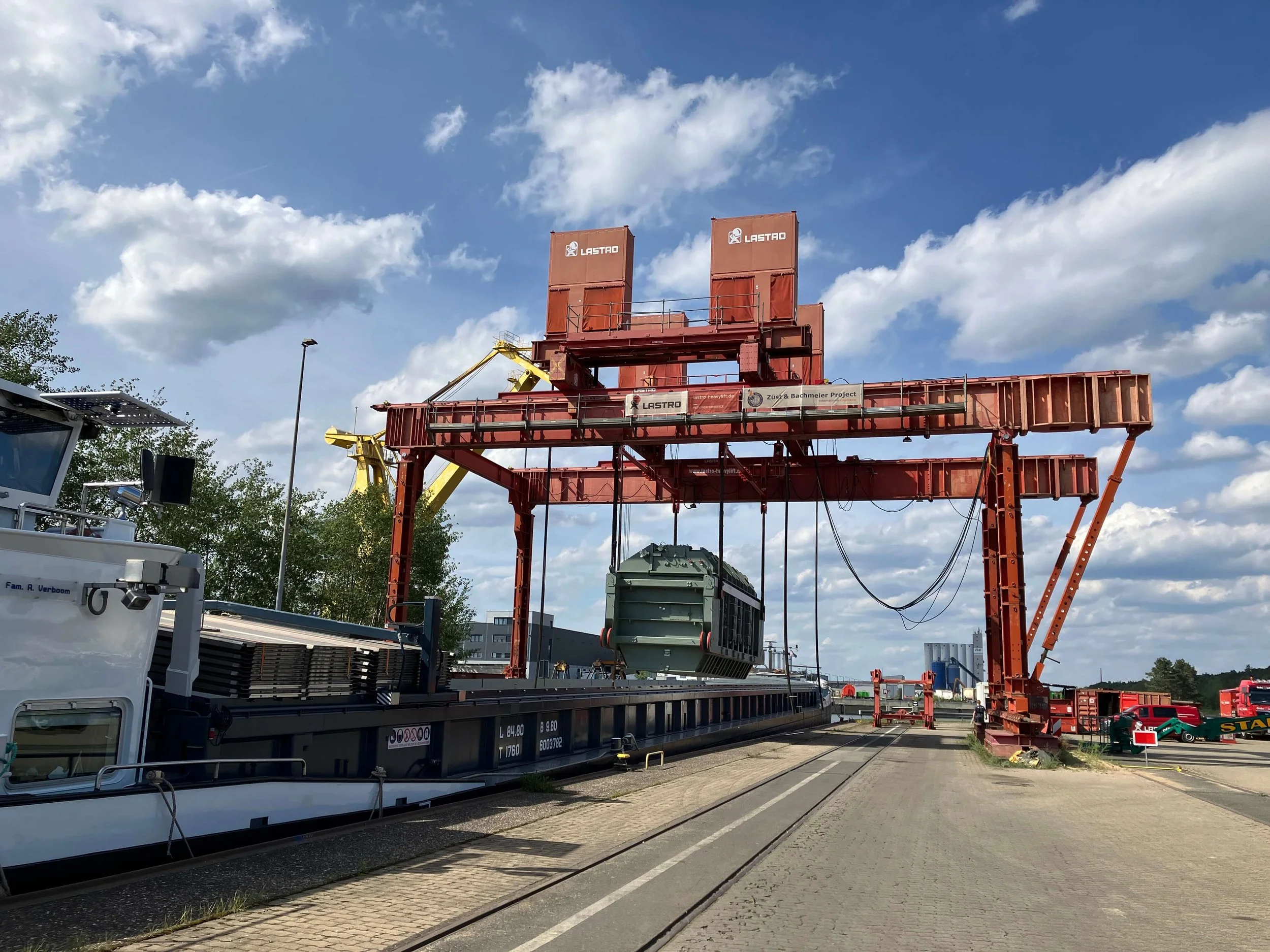 Eine mächtige rote Krananlage am Hafen Nürnberg verlädt Güter von einem Binnenschiff im Bereich des trimodalen Güterverkehrszentrums