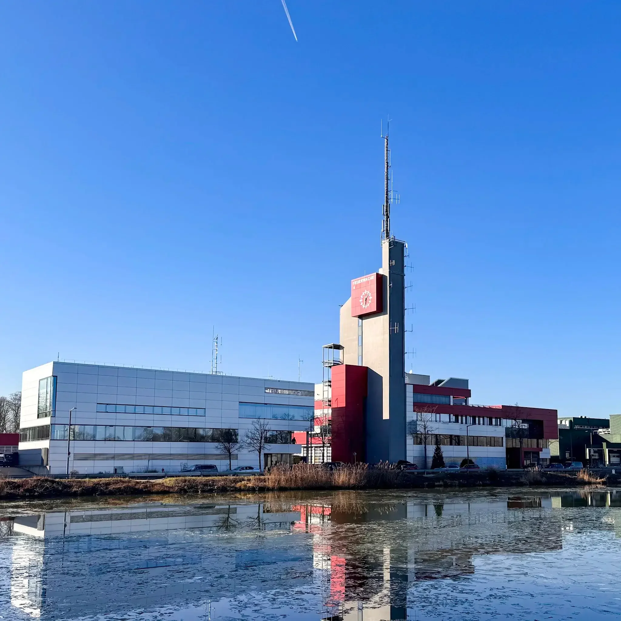 Außenansicht der Feuerwache 4, Integrierten Leitstelle (ILS) in Nürnberg an der Regenstraße mit markantem Turm, die sich im Wasser des Hafenbeckens spiegelt