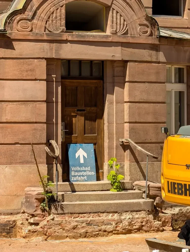 Schild „Volksbad Baustellenzufahrt" vor dem historischen Eingangsportal des Volksbads Nürnberg