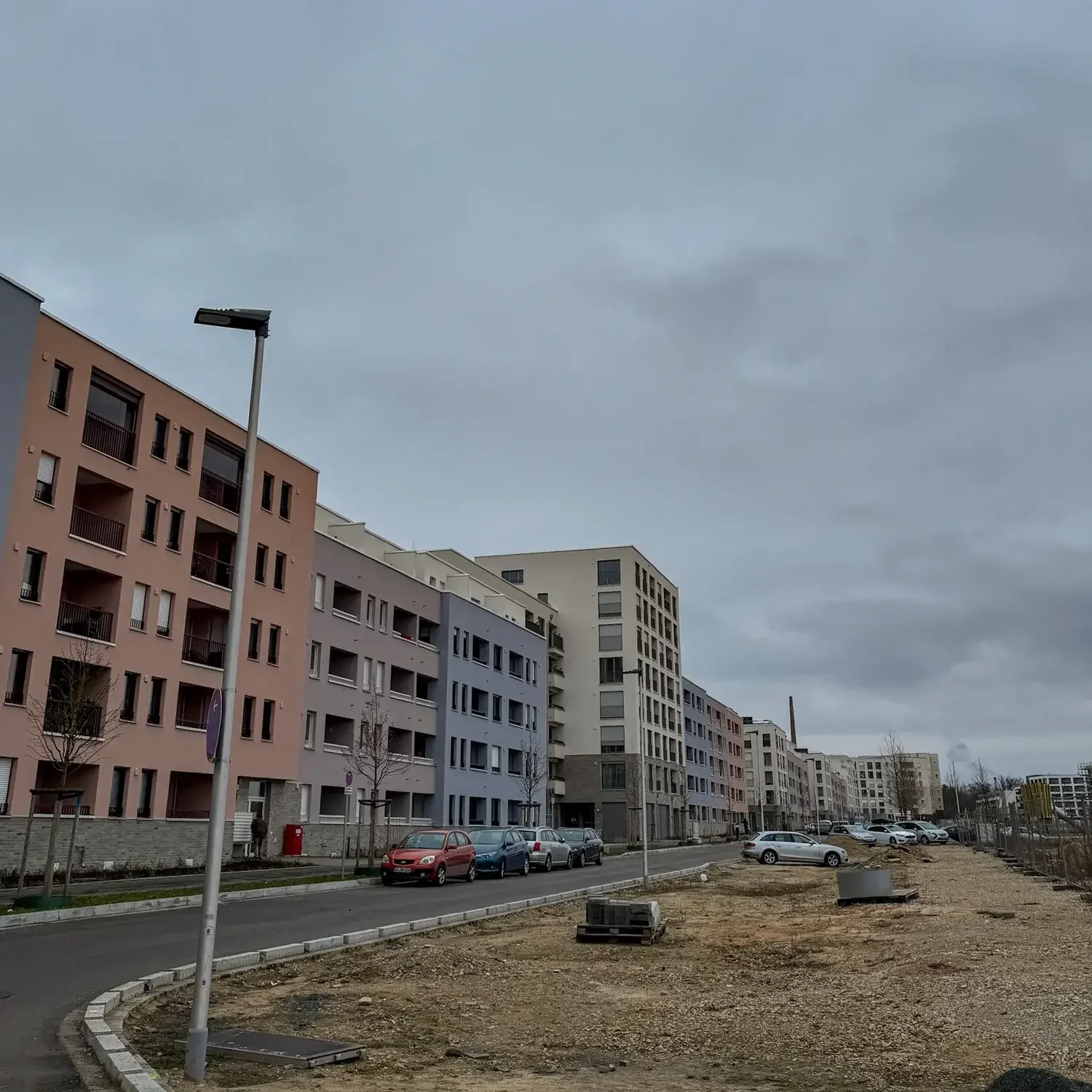 Neubau-Wohnblocks in Nürnberg-Lichtenreuth neben einer Brachfläche unter grauem Himmel.