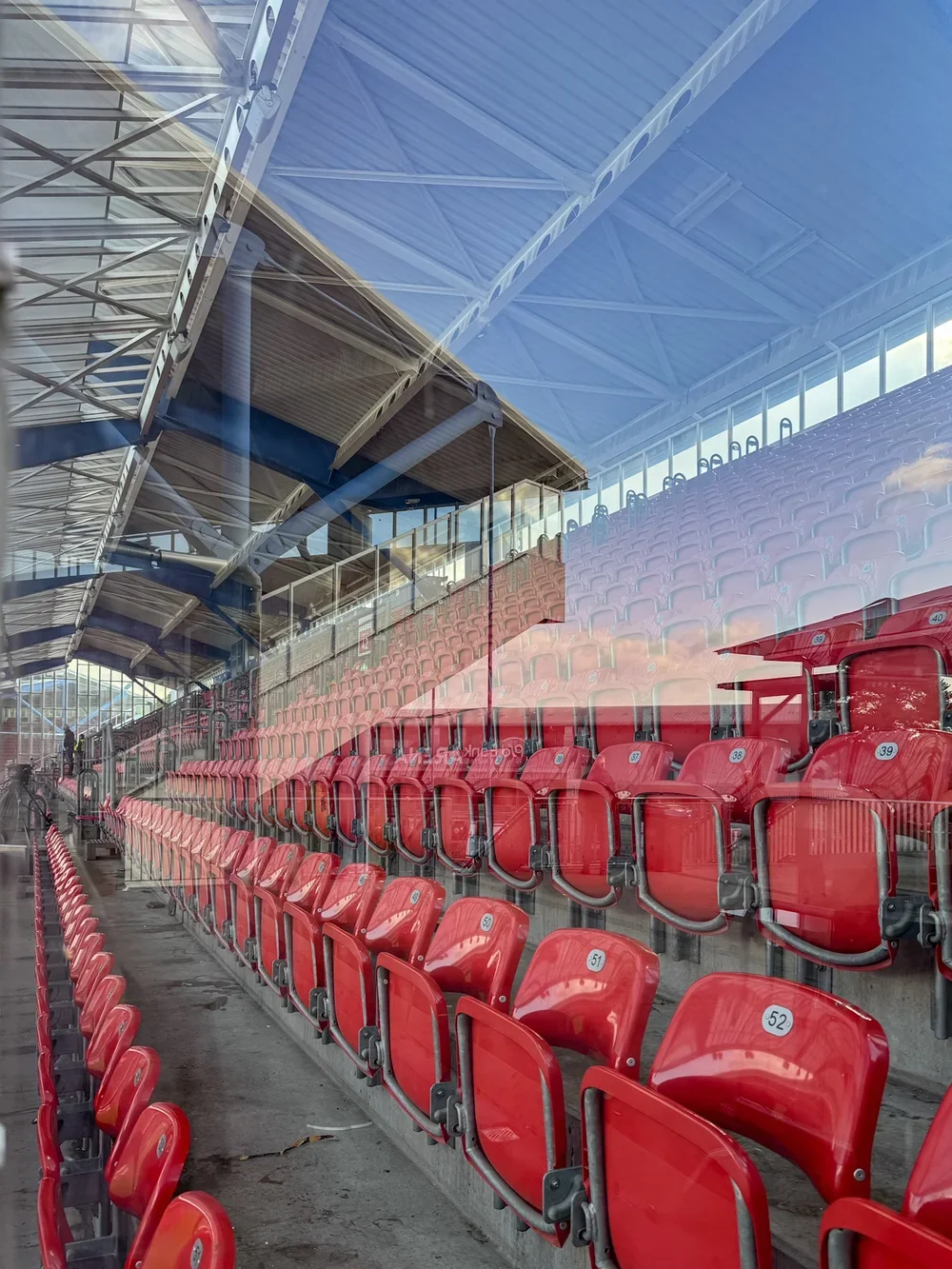 Leere rote Zuschauersitze im Max-Morlock-Stadion Nürnberg hinter einer Glasscheibe