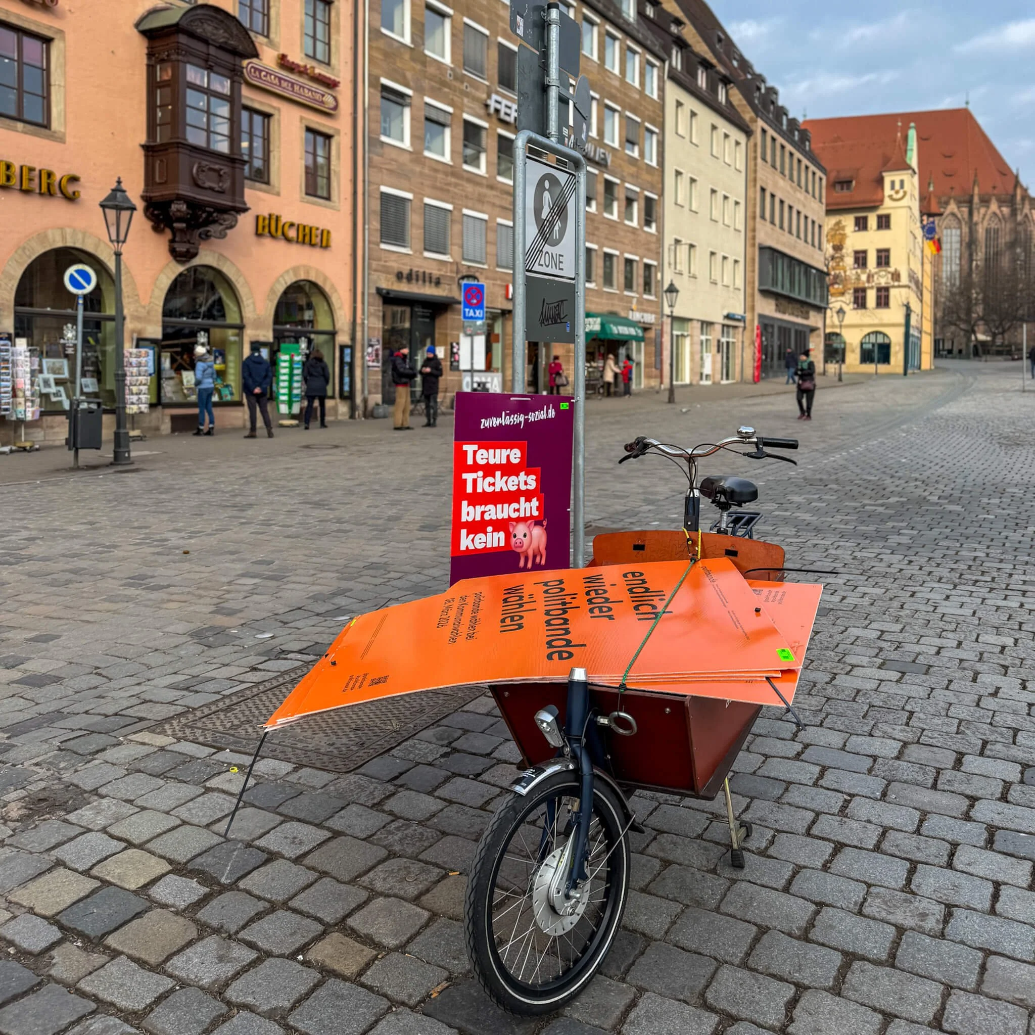 Lastenrad am Nürnberger Hauptmarkt beladen mit orangen Wahlplakaten der Wählervereinigung "Politbande" – Symbol für den fragmentierten Kommunalwahlkampf.