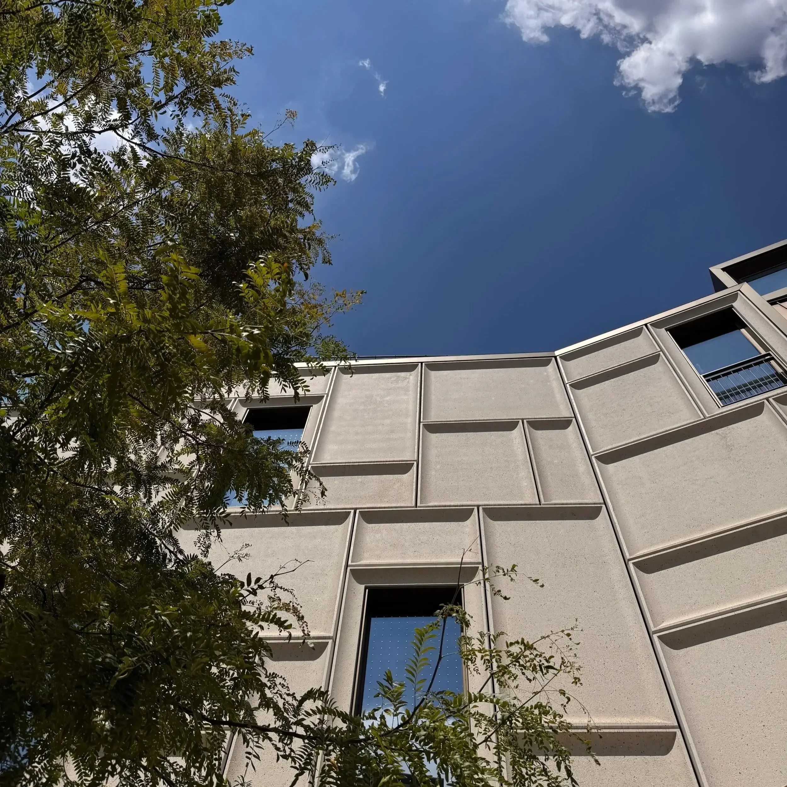 Die moderne, helle Fassade des Zukunftsmuseums am Nürnberger Augustinerhof unter blauem Himmel.