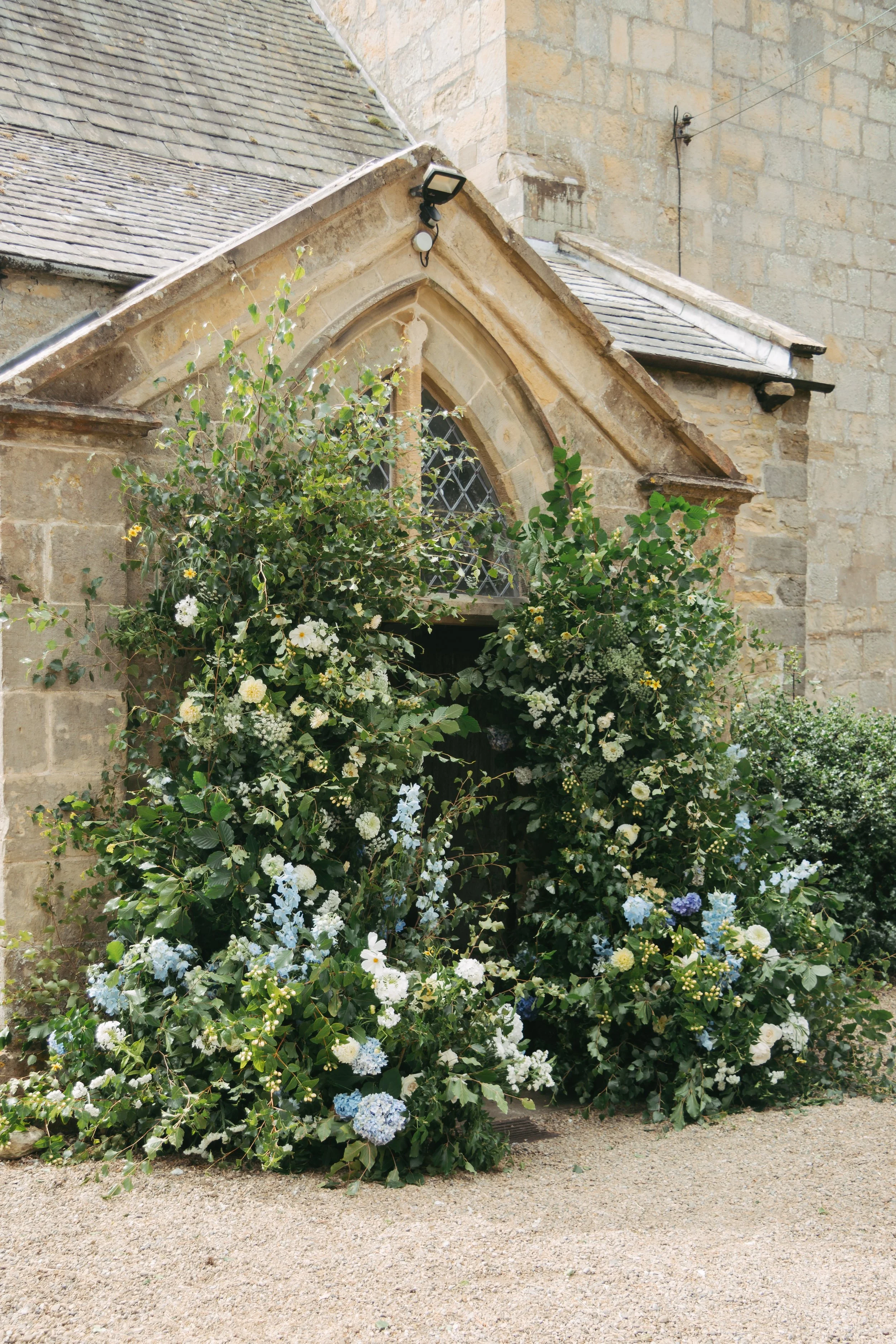 An abundant broken archway for a church wedding, framing the church entrance in a village in Yorkshire