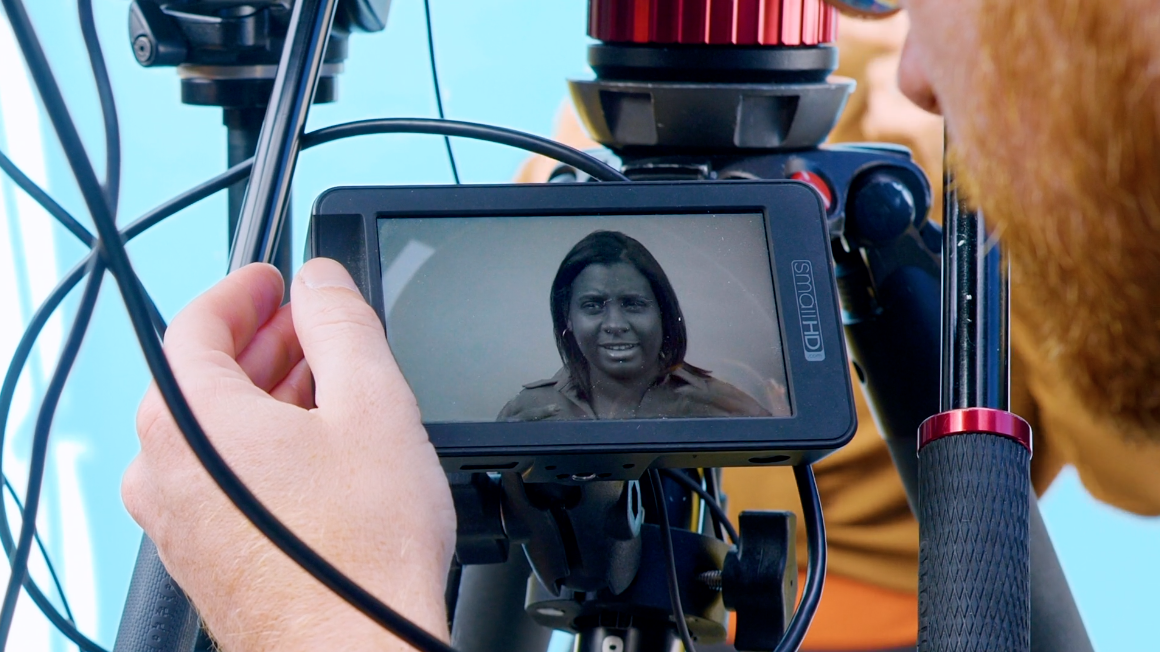 A camera operator looking at a field monitor during the filming of a skincare commercial.