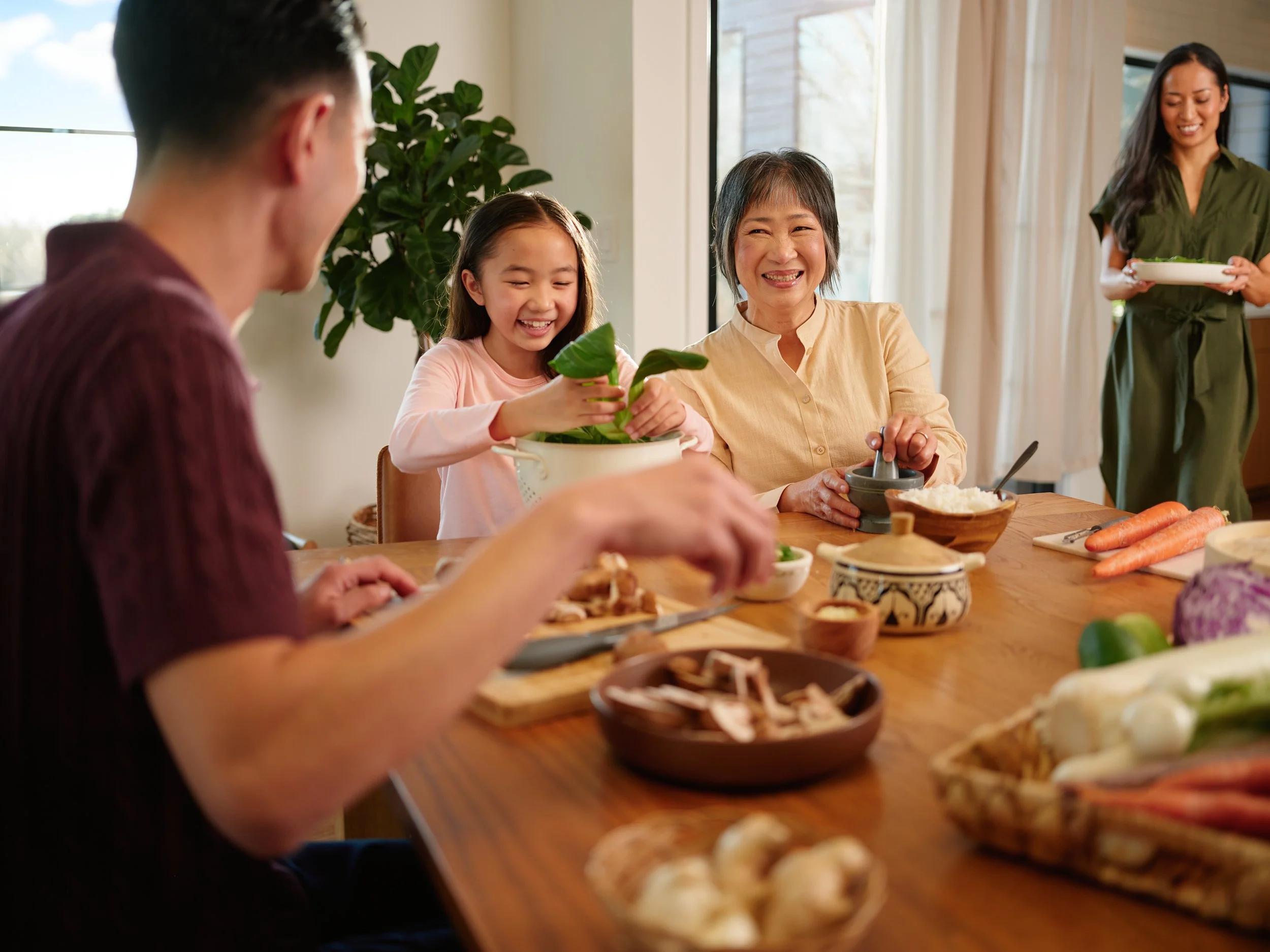Family sitting together at a dining table sharing a meal, representing health and wellbeing lifestyle in Amway brand photography.