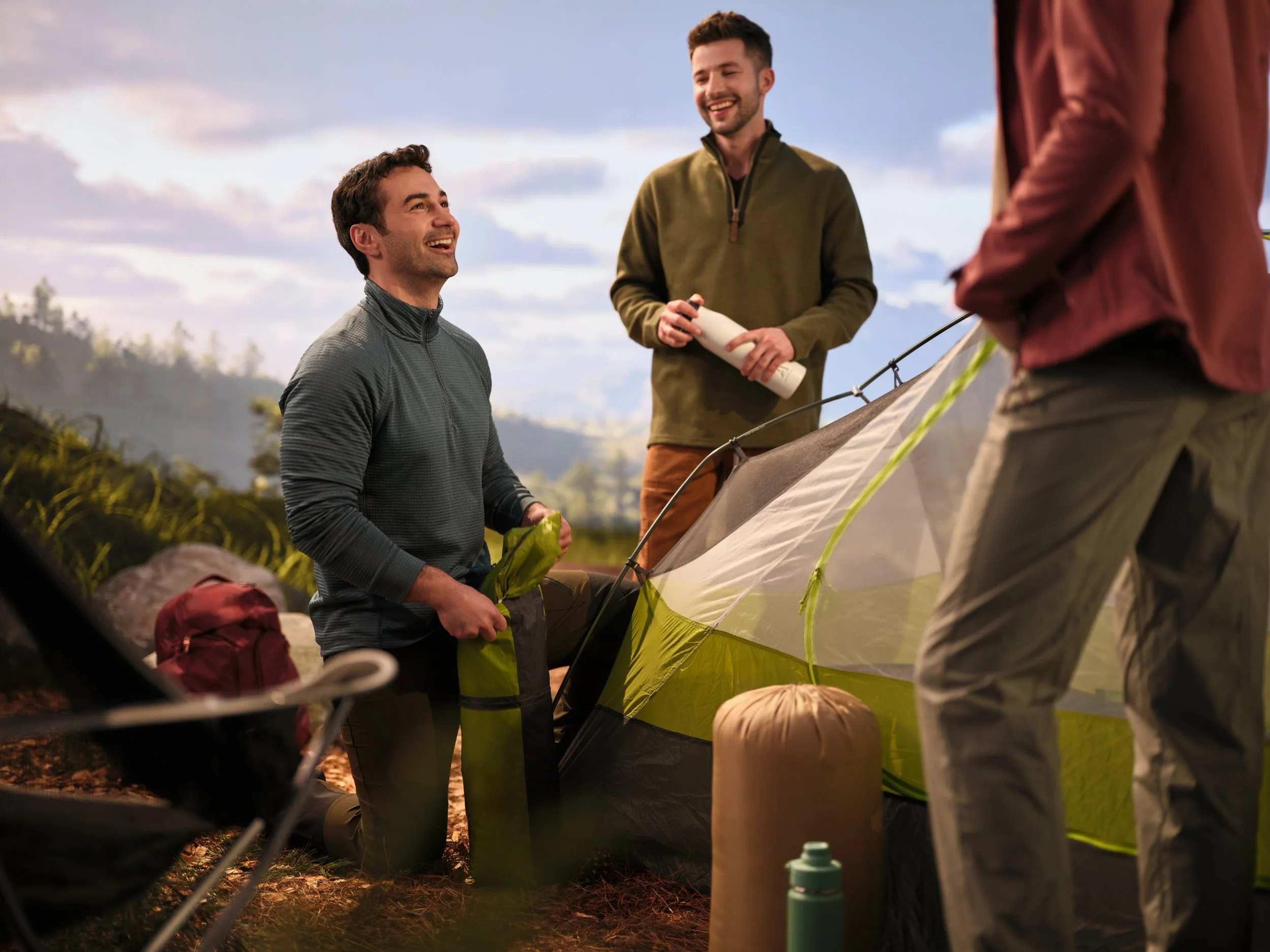 Man smiling and looking up at friends while camping outdoors.