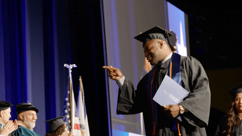 APU students walking across stage at 2025 graduation.