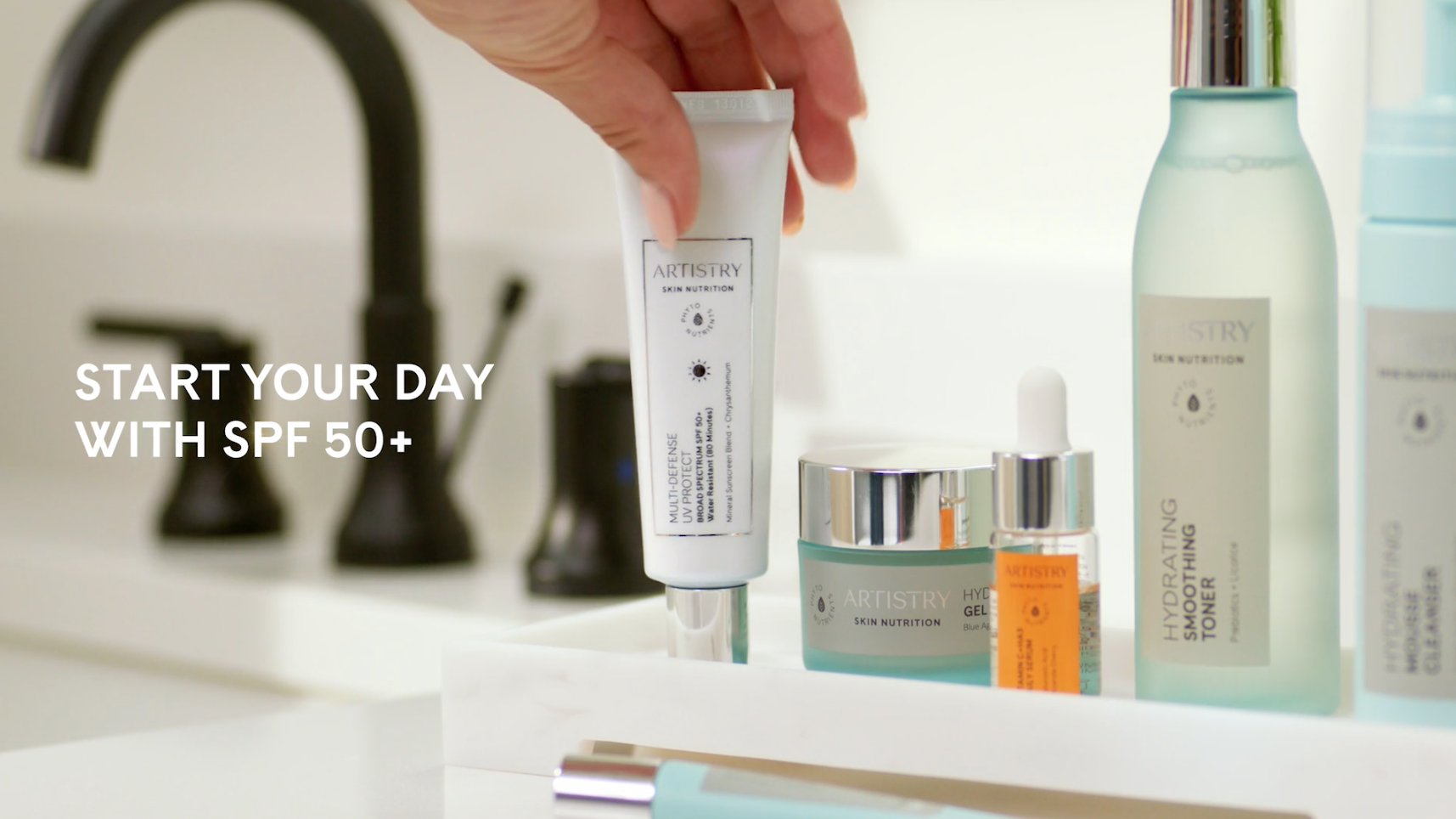 Close-up of Amway Artistry UV 50 and other products on a bathroom counter tray.