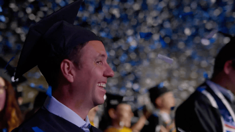 APU graduates celebrating at 2025 commencement with confetti falling.