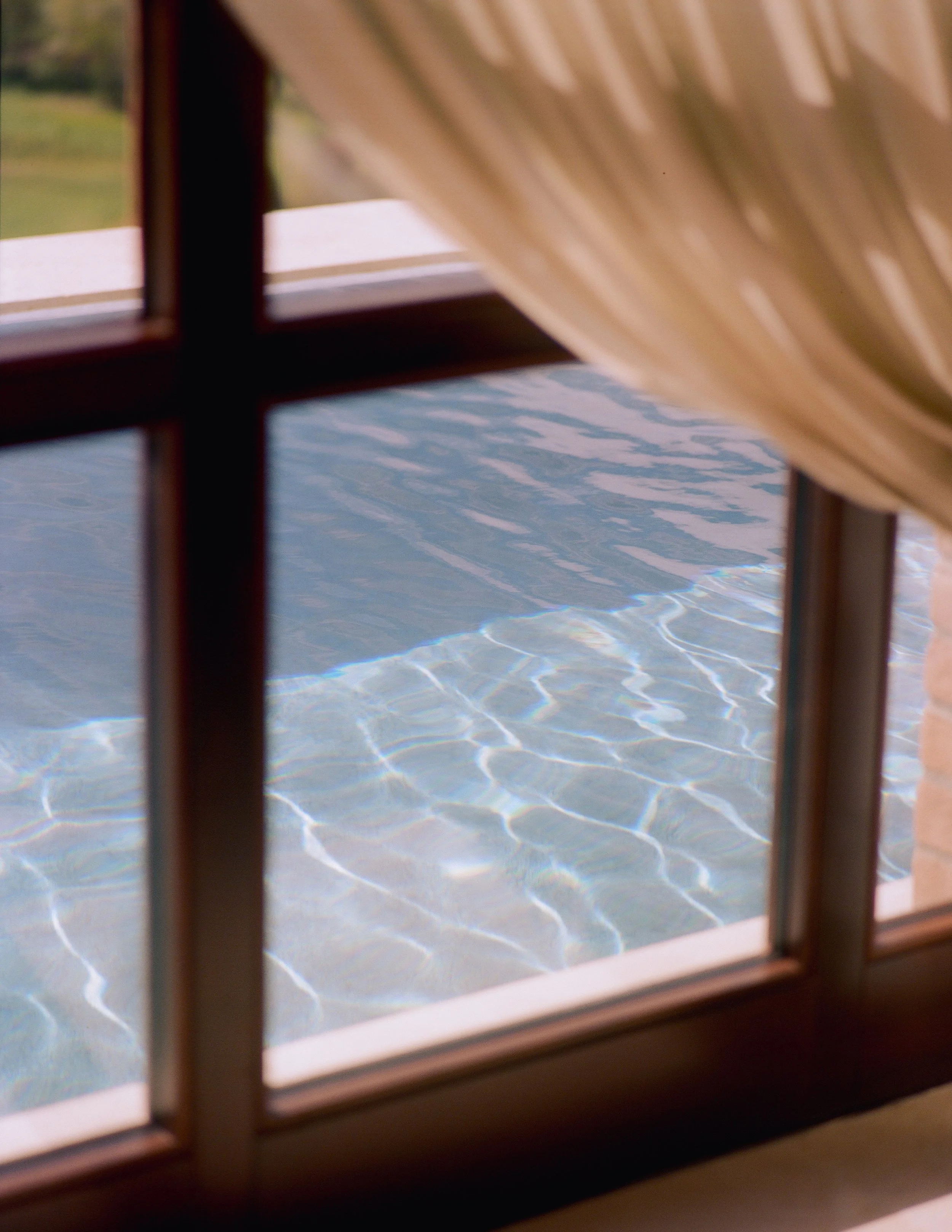 hotel pool through a window with a curtain
